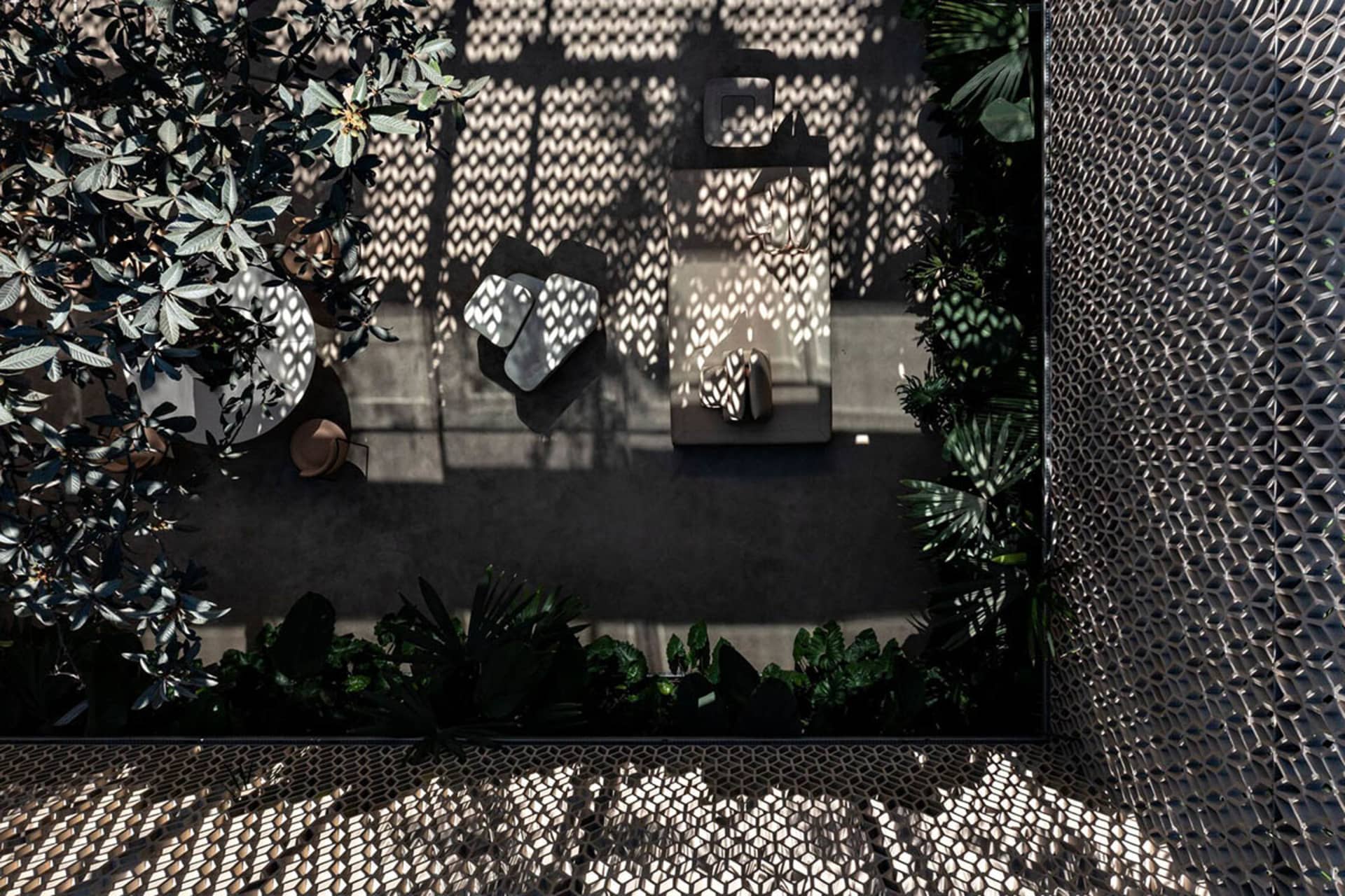 Modern minimalist garden featuring concrete walls with intricate patterns