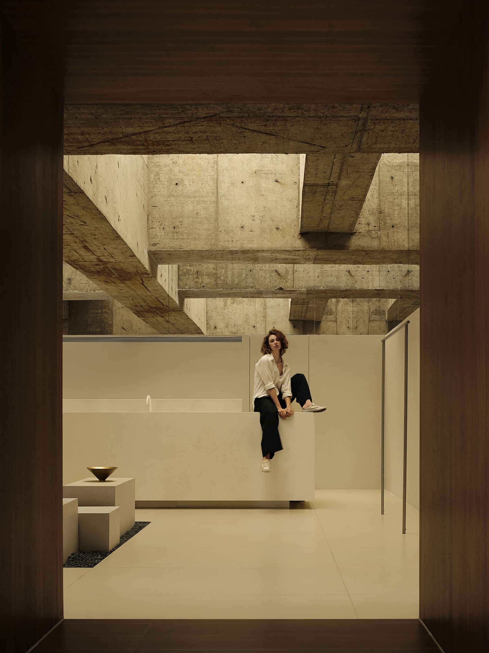 一位女子坐在現代室內空間的混凝土牆上。