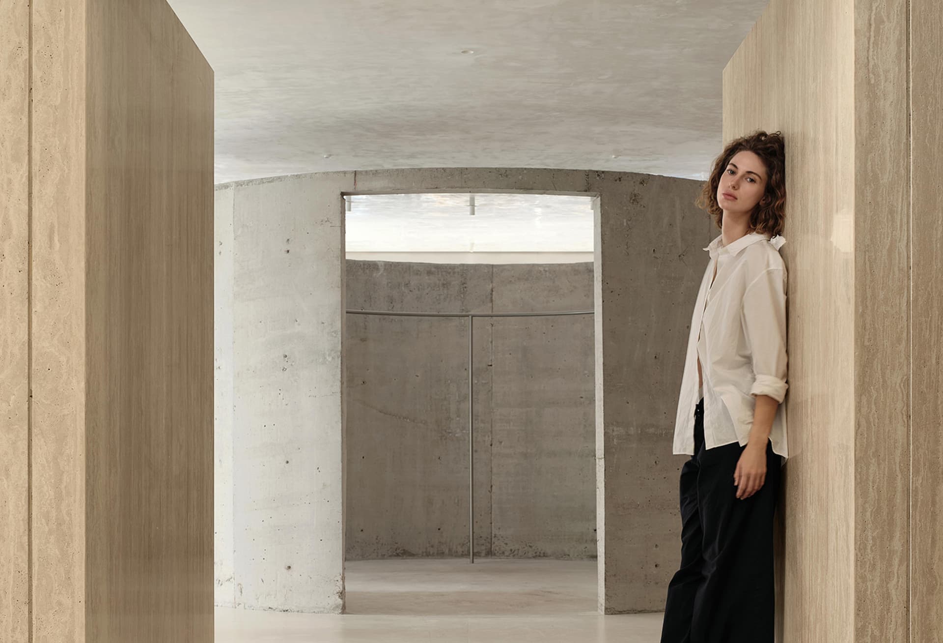 A minimalist interior scene featuring concrete walls and a light source through a window.