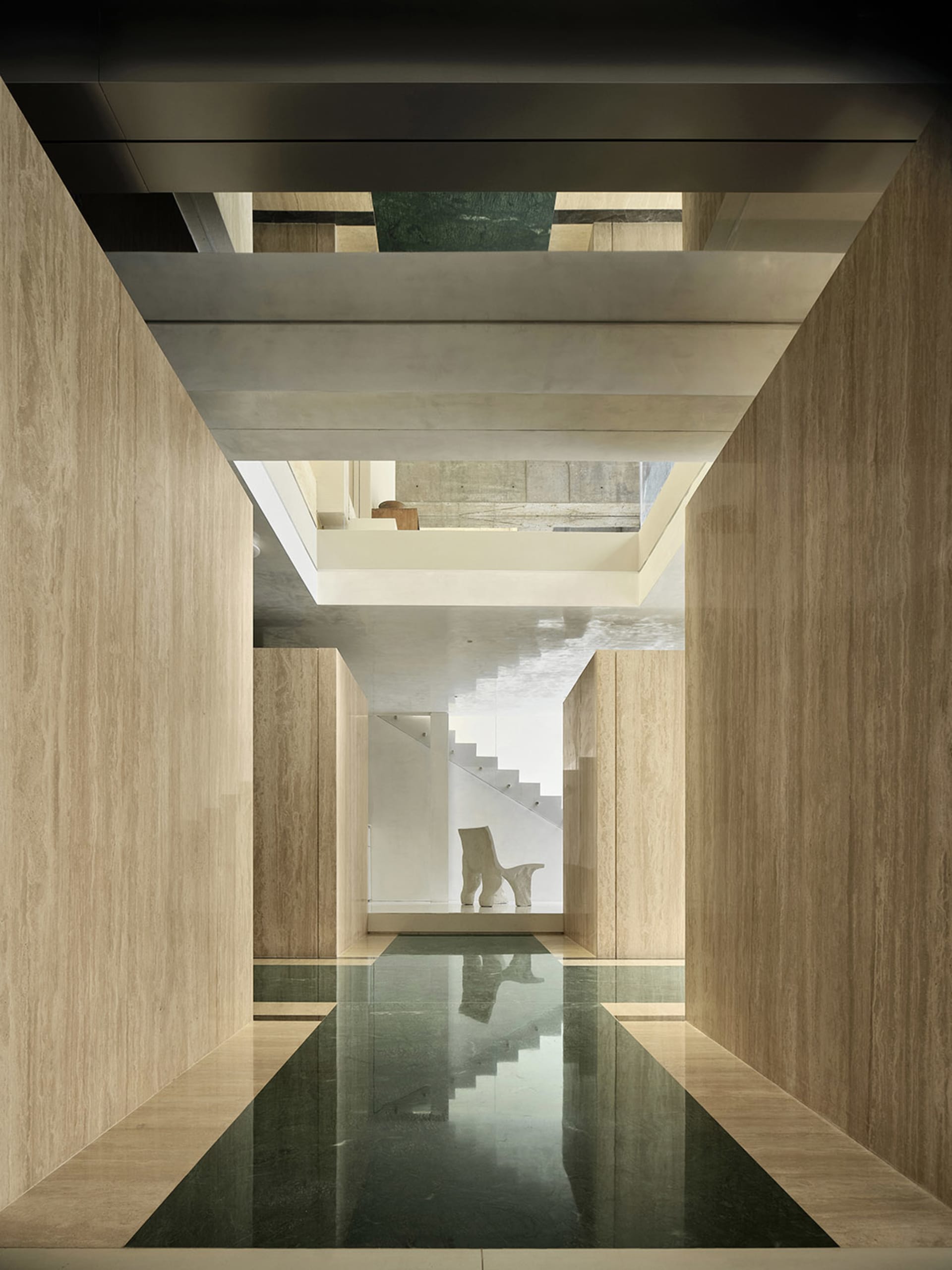 A modern interior space featuring concrete walls, natural light, and a minimalist design with a sleek, black floor.