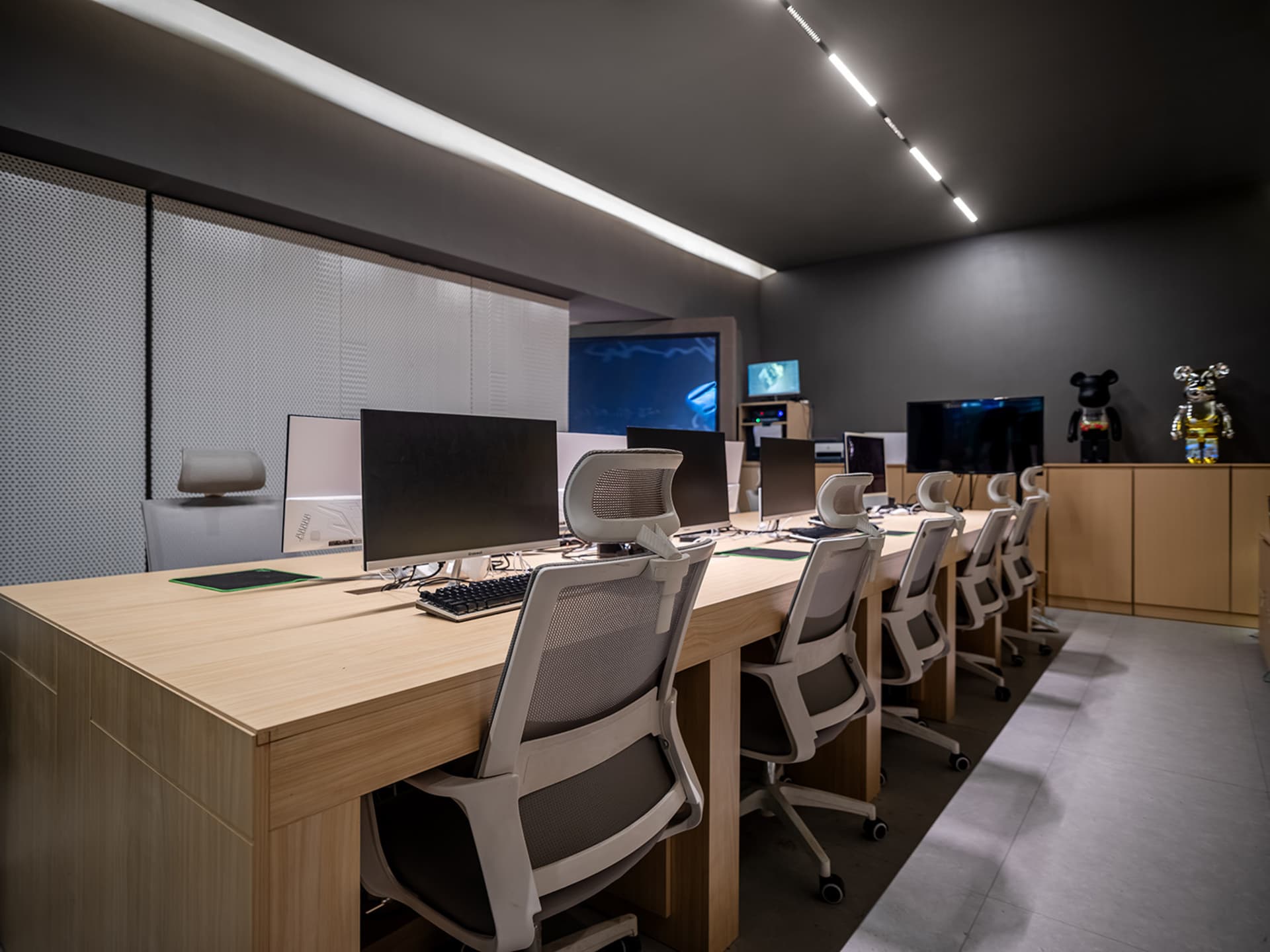 A modern, minimalist workspace desk setup with white chairs, desks, and computers.