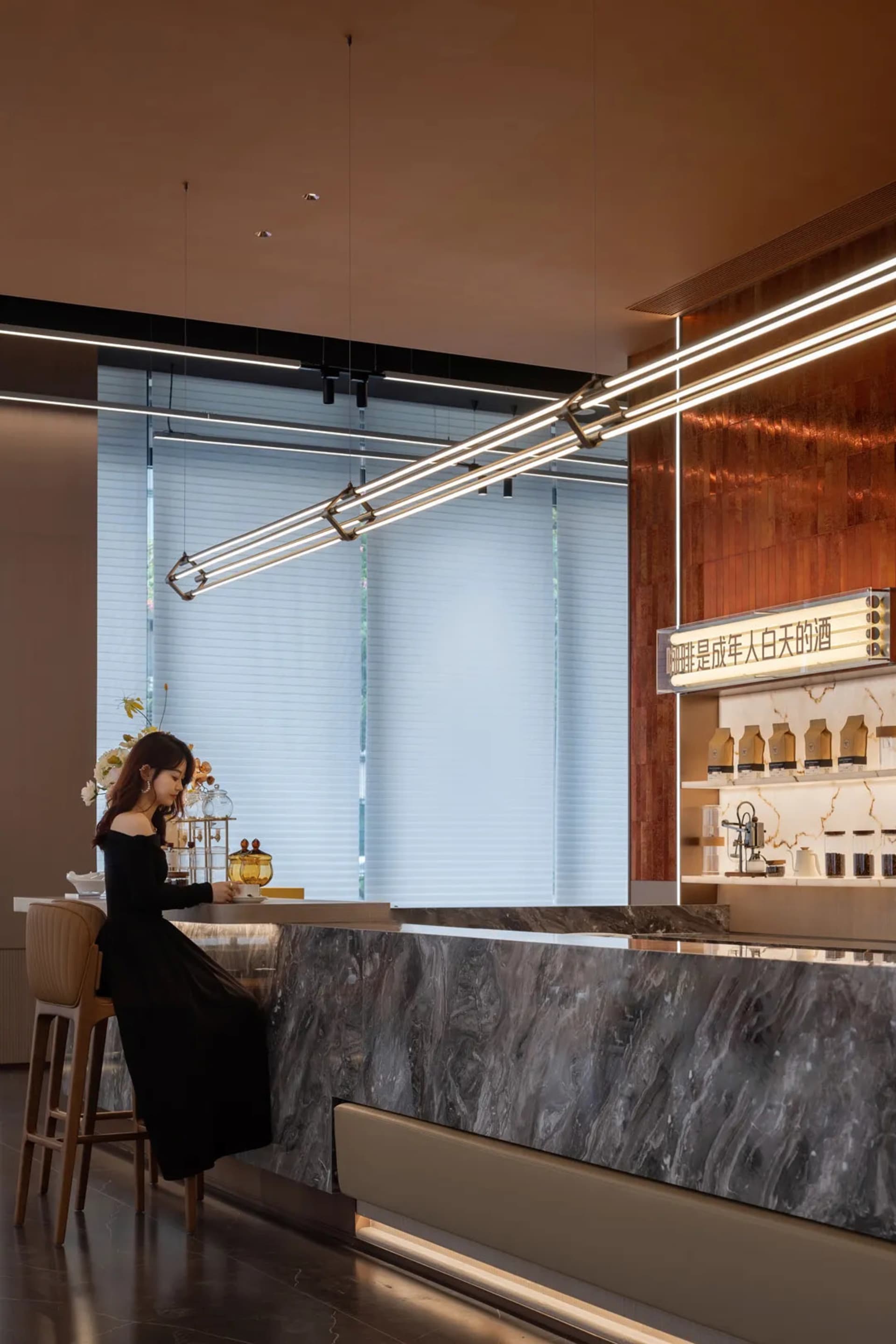 A stylish modern coffee bar with sleek marble countertops, illuminated by contemporary lighting fixtures, and featuring a gla