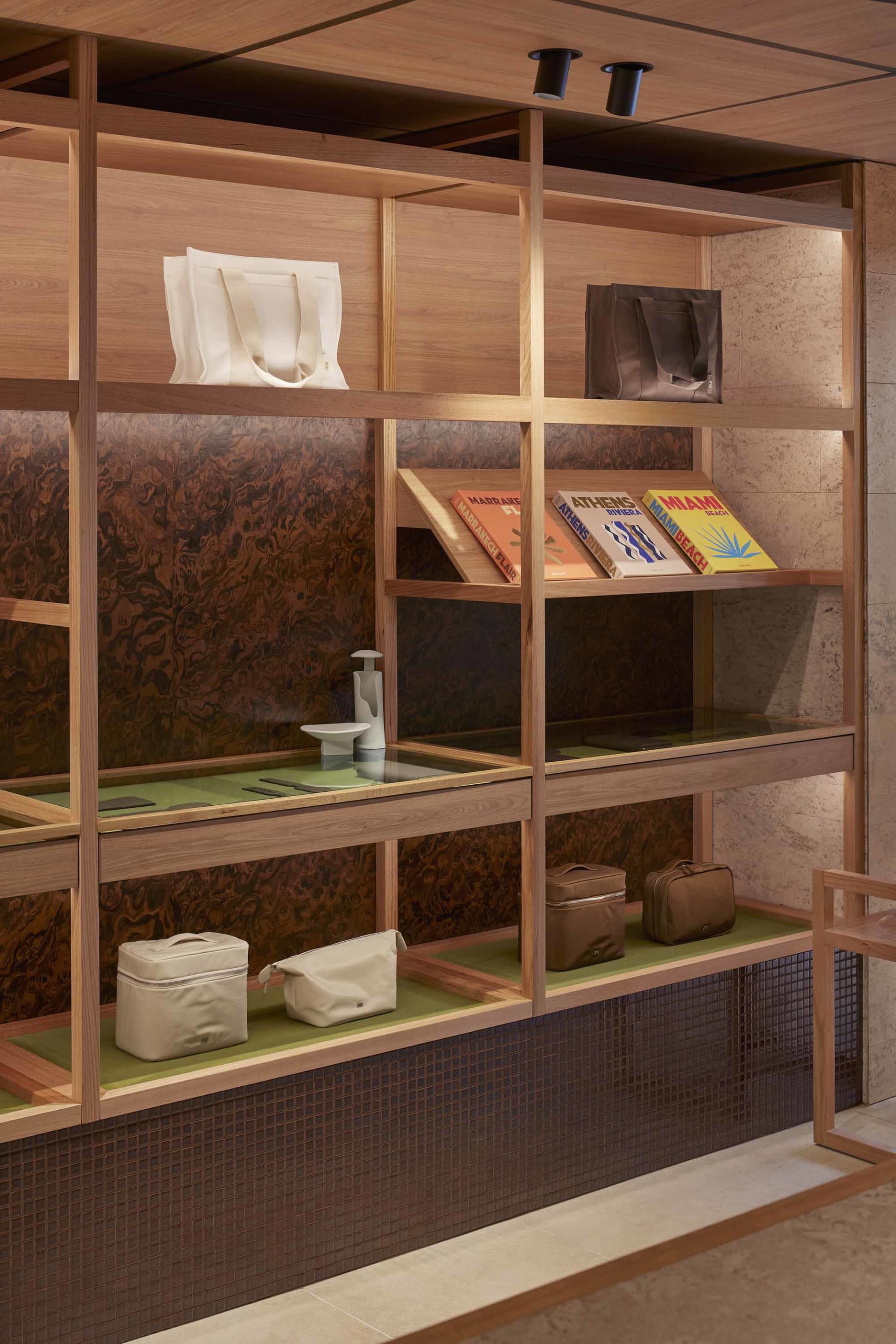 Modern retail storefront with wooden laminate shelving displaying bags and books.
