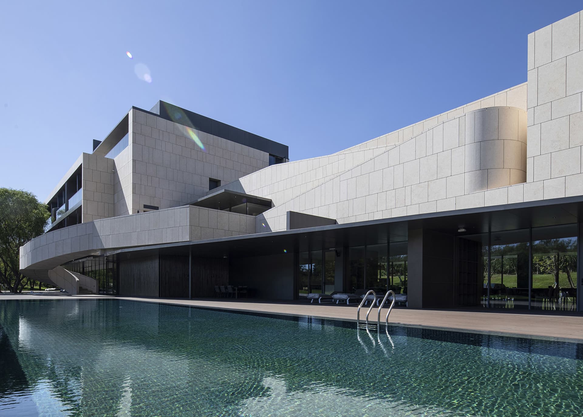Modern architectural building with a stone exterior featuring clean lines and a curved design.