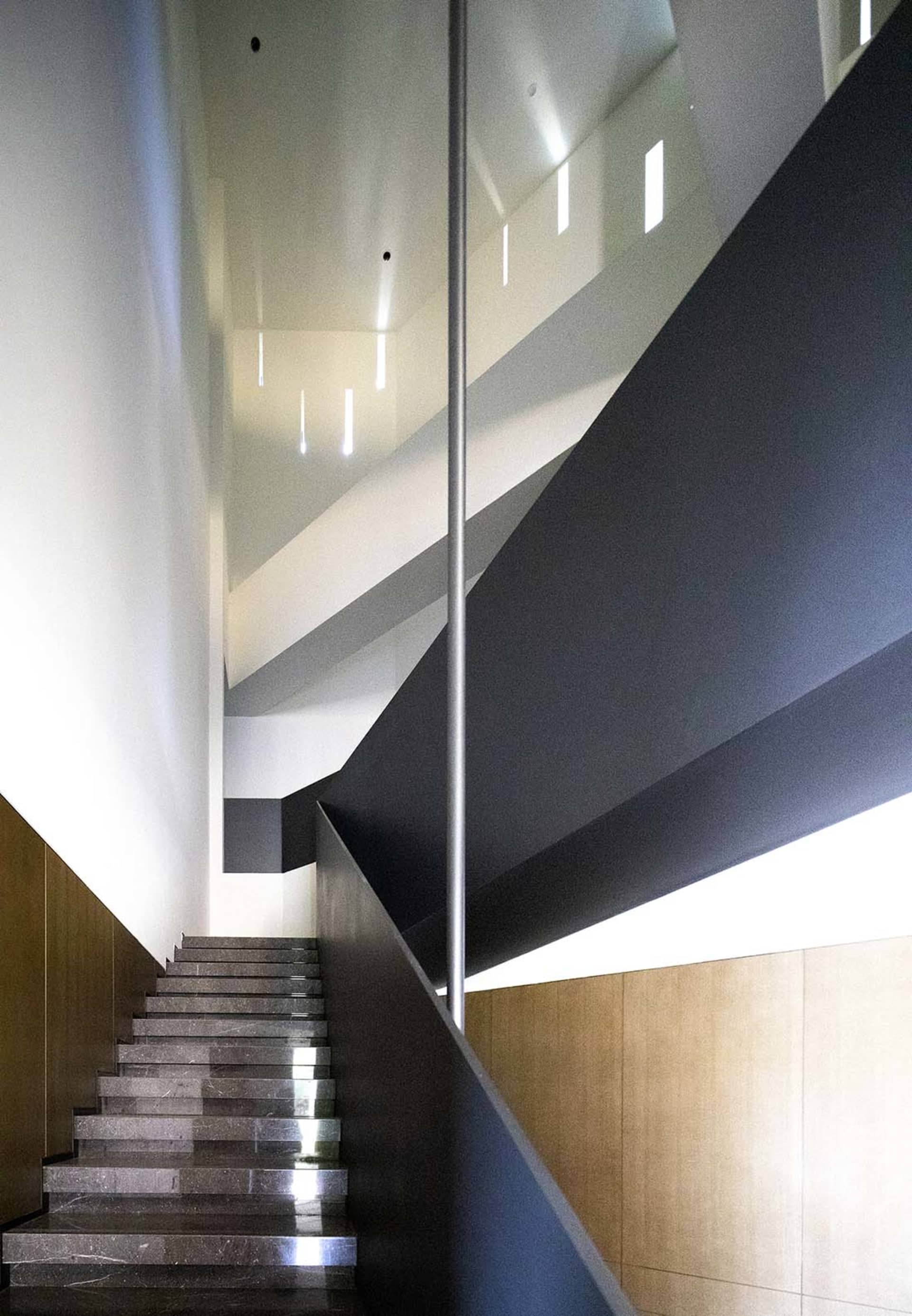 A modern staircase with glass and concrete materials.