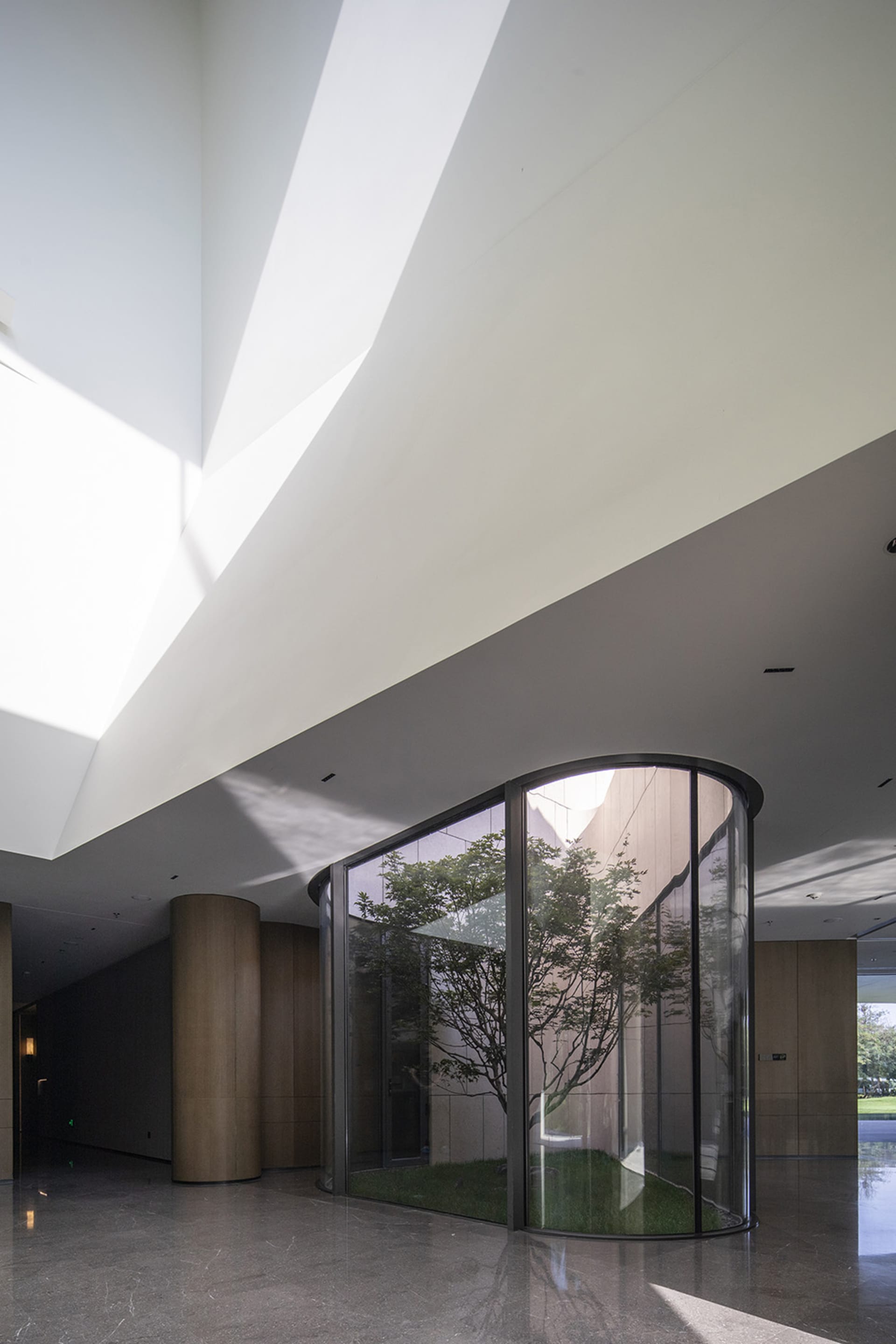 A modern lobby featuring glass walls and concrete pillars.