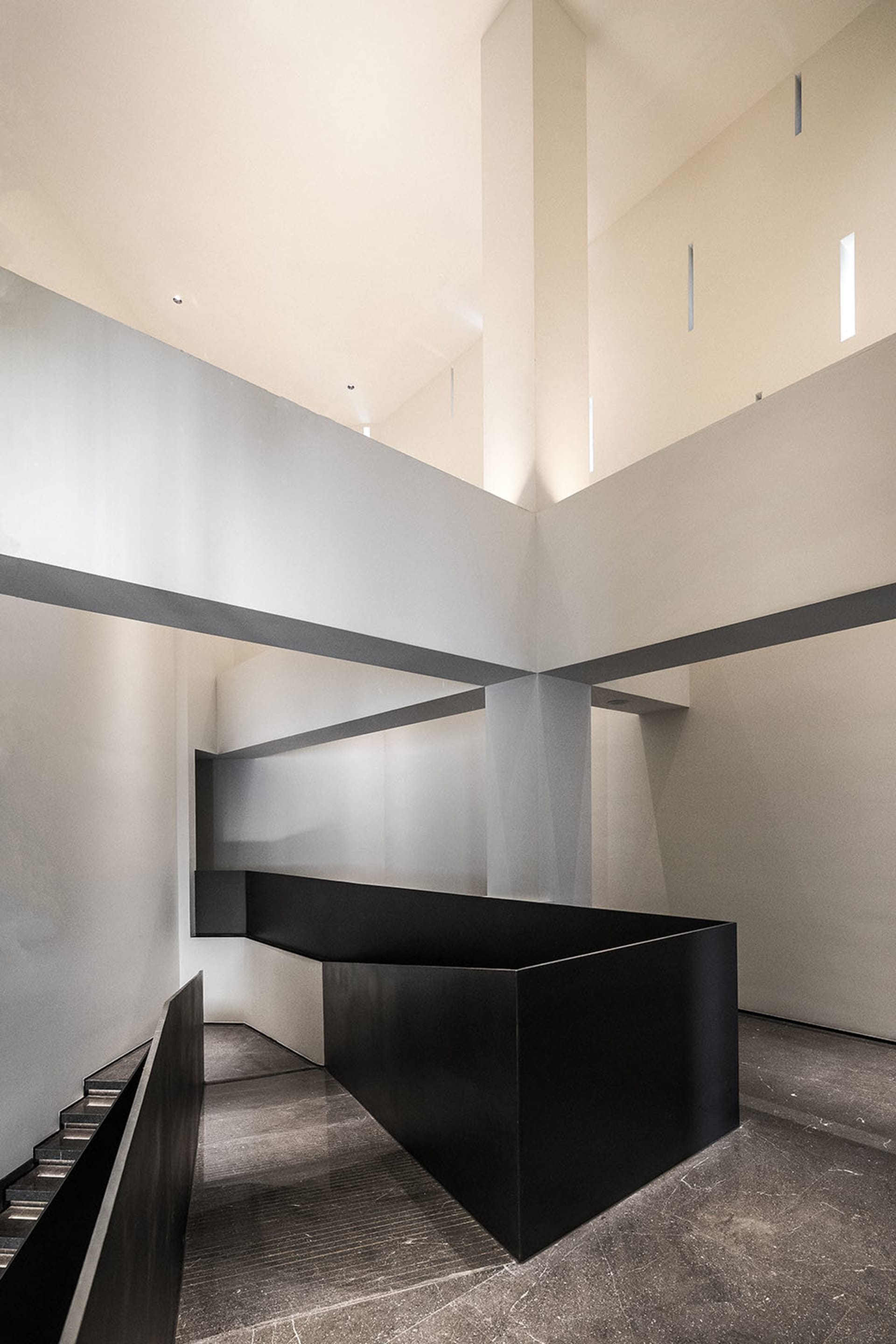 A contemporary interior space featuring a black cube structure and concrete walls and floor.