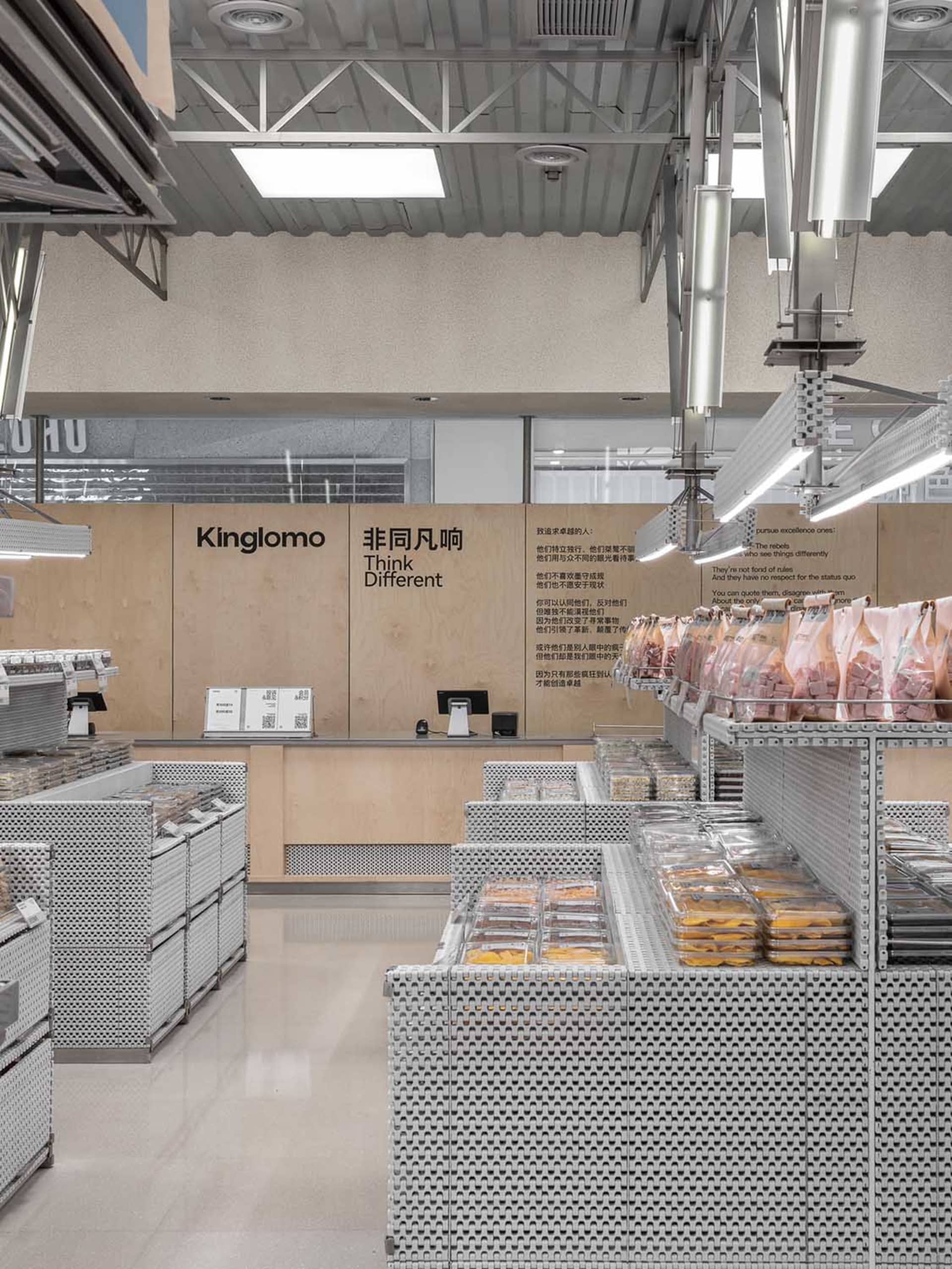 A modern grocery store with metallic shelving, well-lit ceiling lights, and a checkout counter.