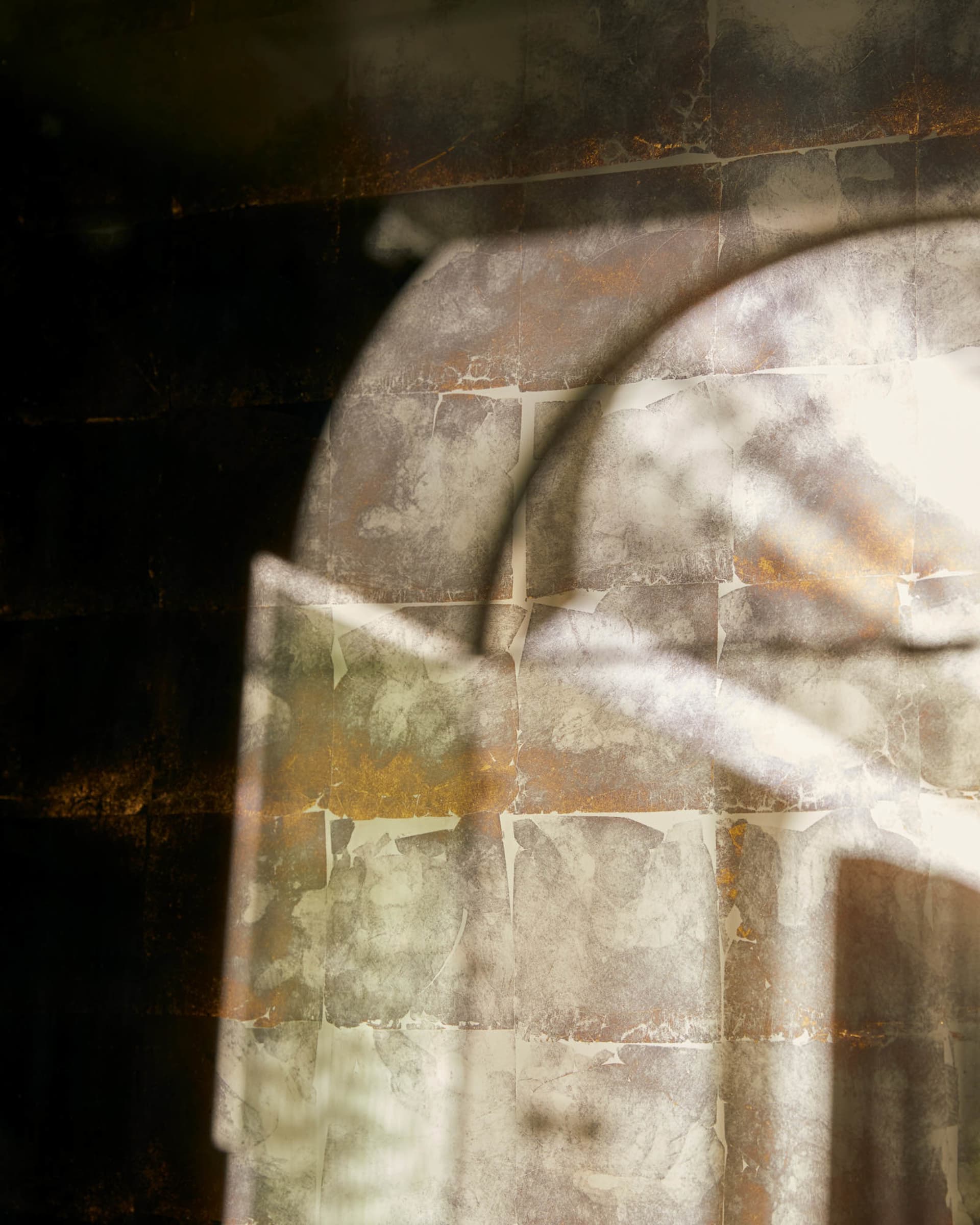 A textured fabric with geometric patterns illuminated by light filtering through a window, creating an abstract shadow design