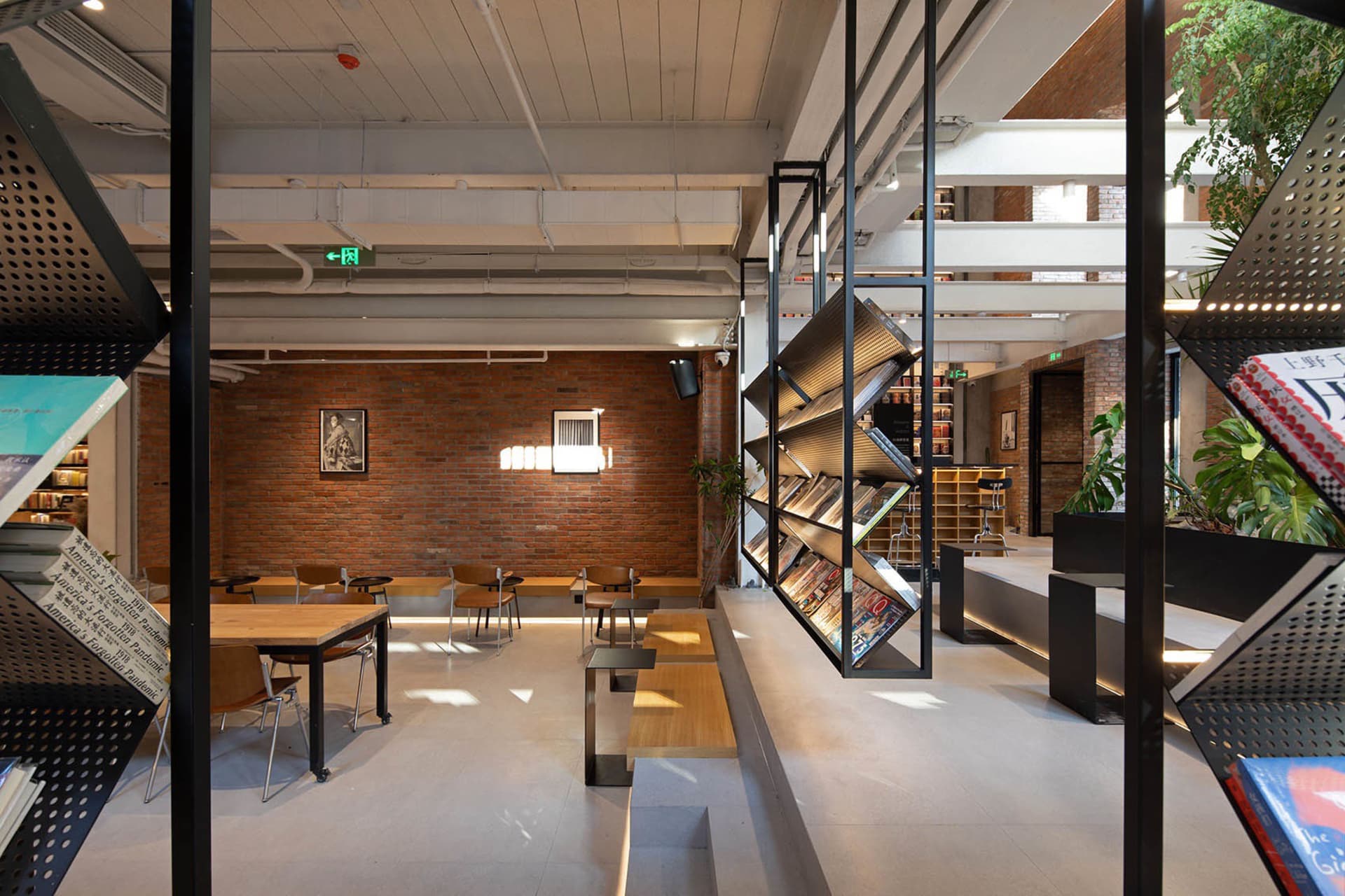A spacious industrial-style library interior with modern furniture and bookshelves filled with books.