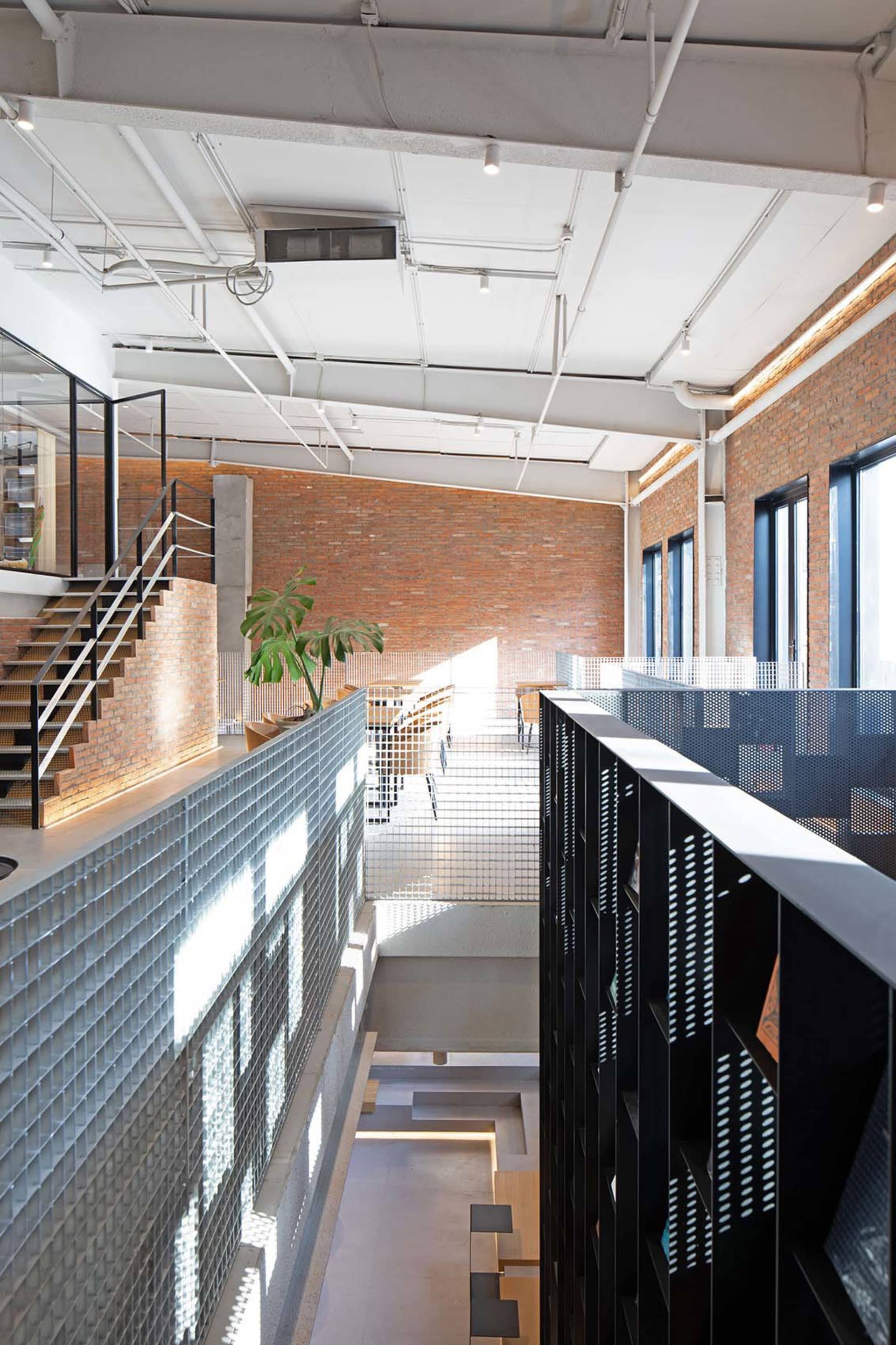 An industrial-style office space featuring brick walls, glass elements, and concrete finishes.