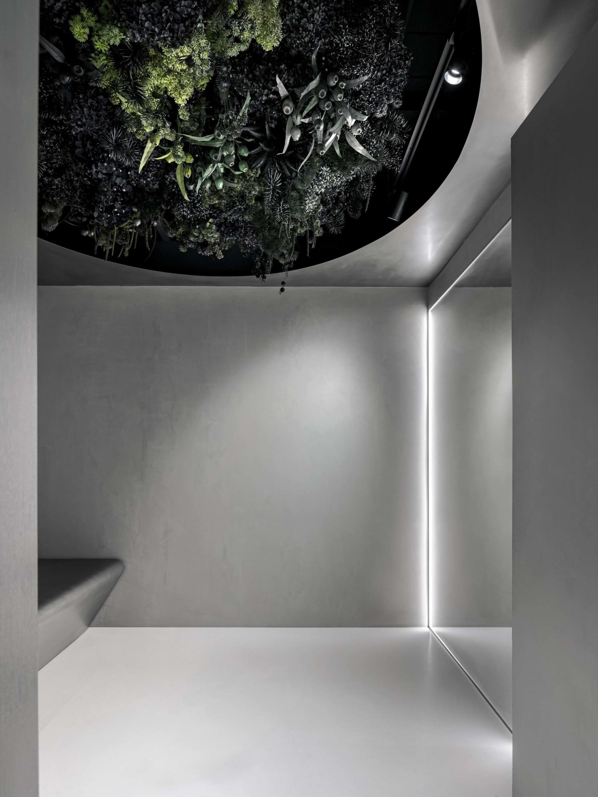 Industrial-style interior with vertical greenery, featuring a variety of artificial plants mounted on a concrete wall.
