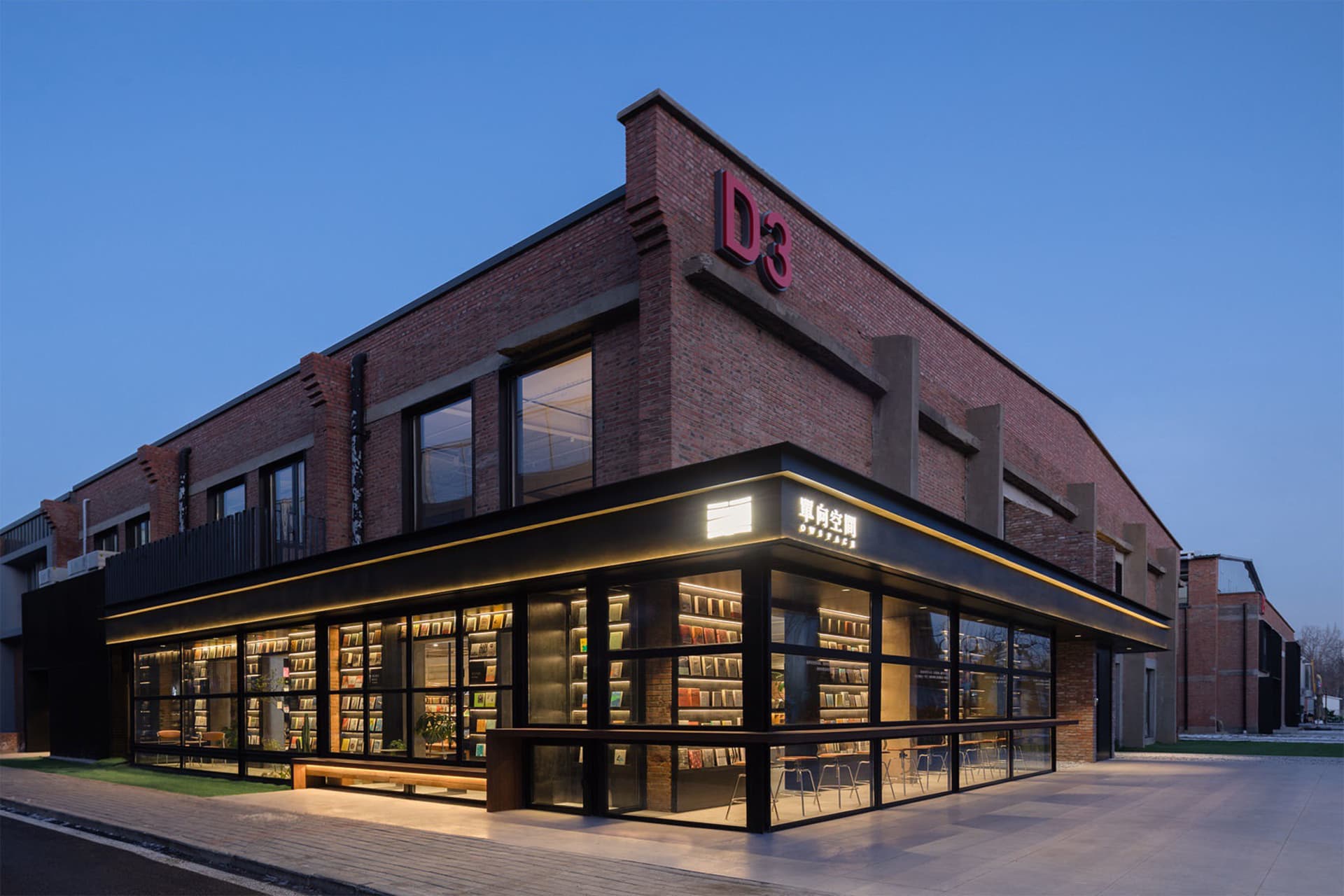 A modern bookstore interior with brick walls, concrete floors, and abundant glass windows.
