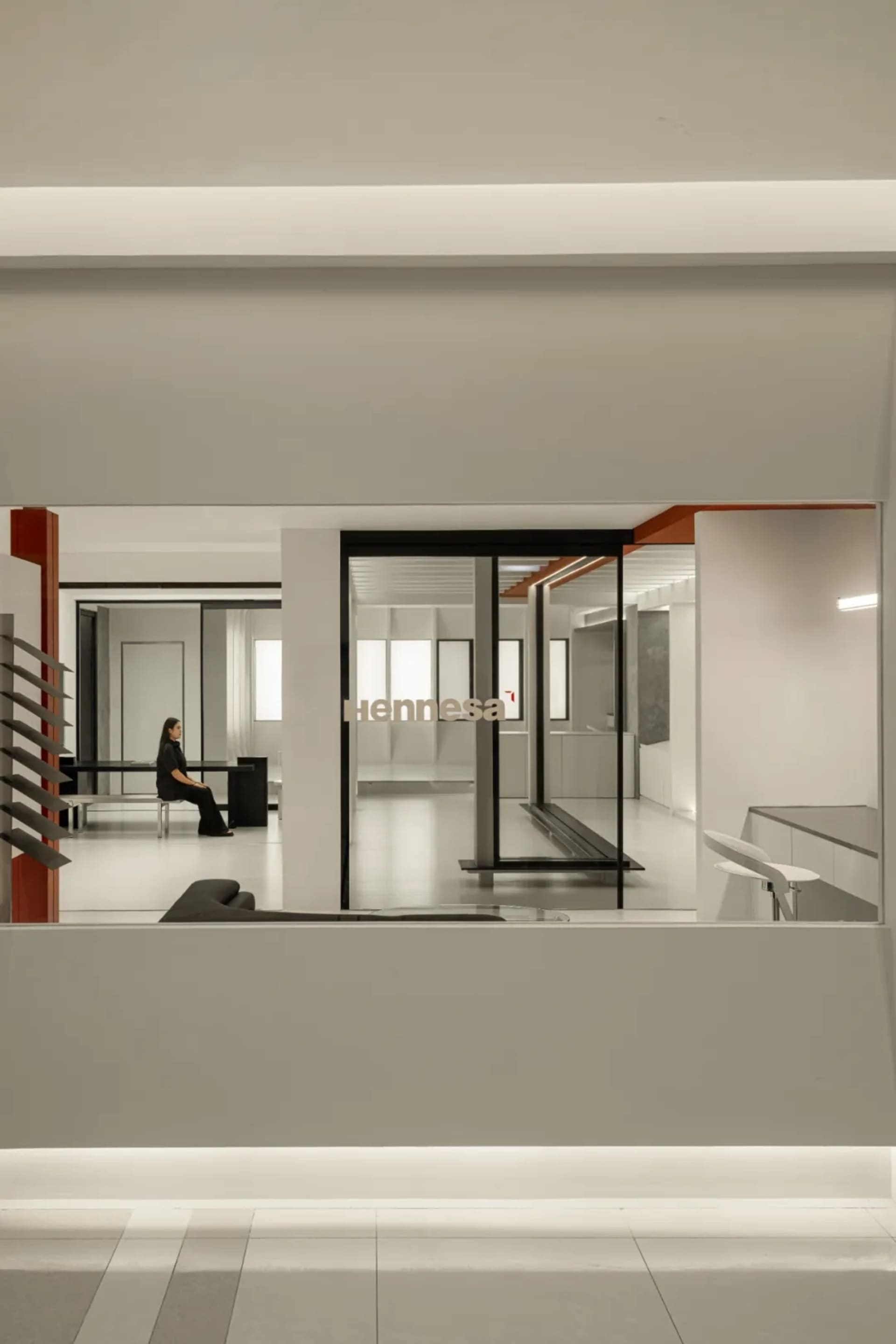 A modern office space with transparent glass walls and floor-to-ceiling windows.