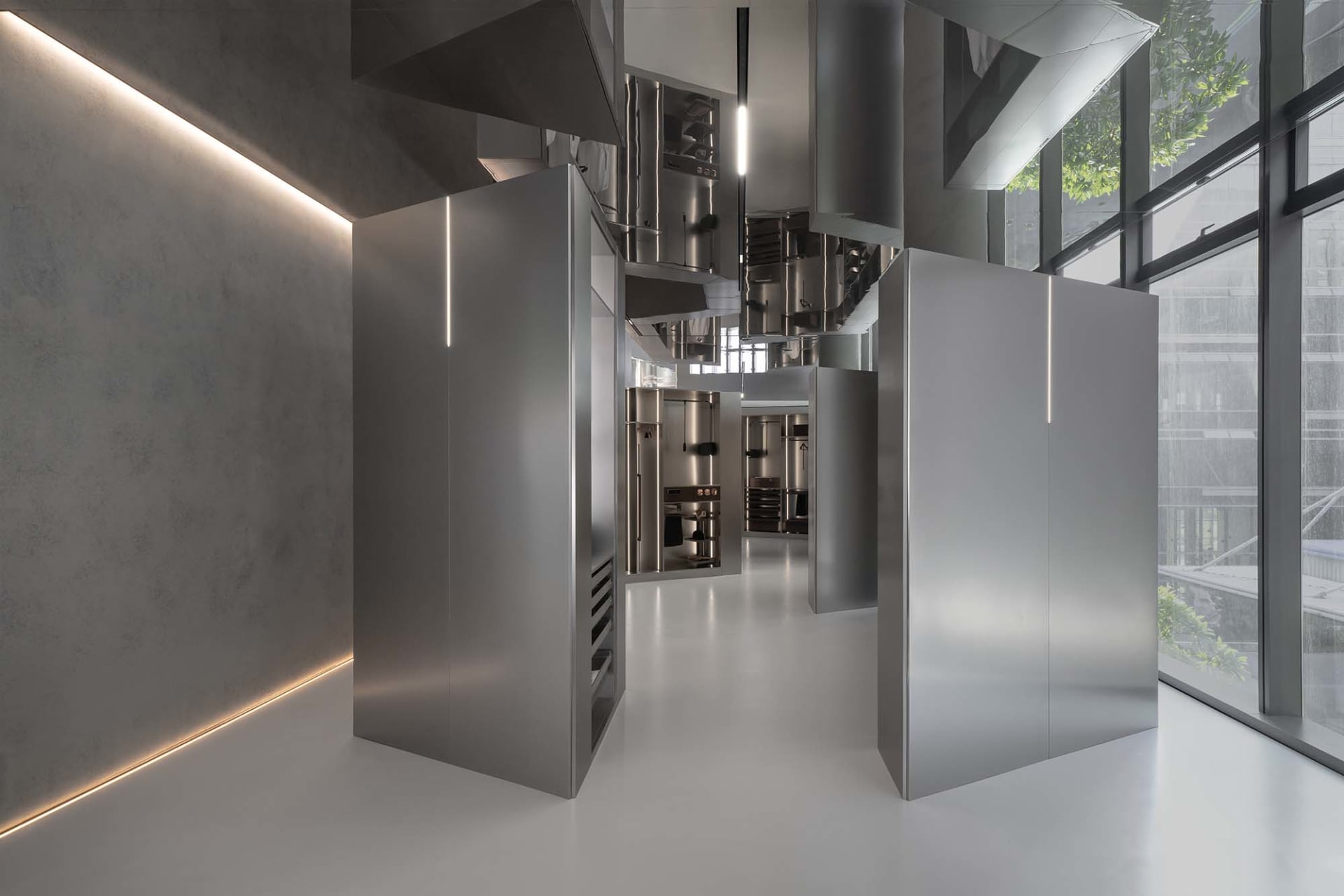 Modern industrial commercial kitchen with stainless steel appliances and concrete flooring.