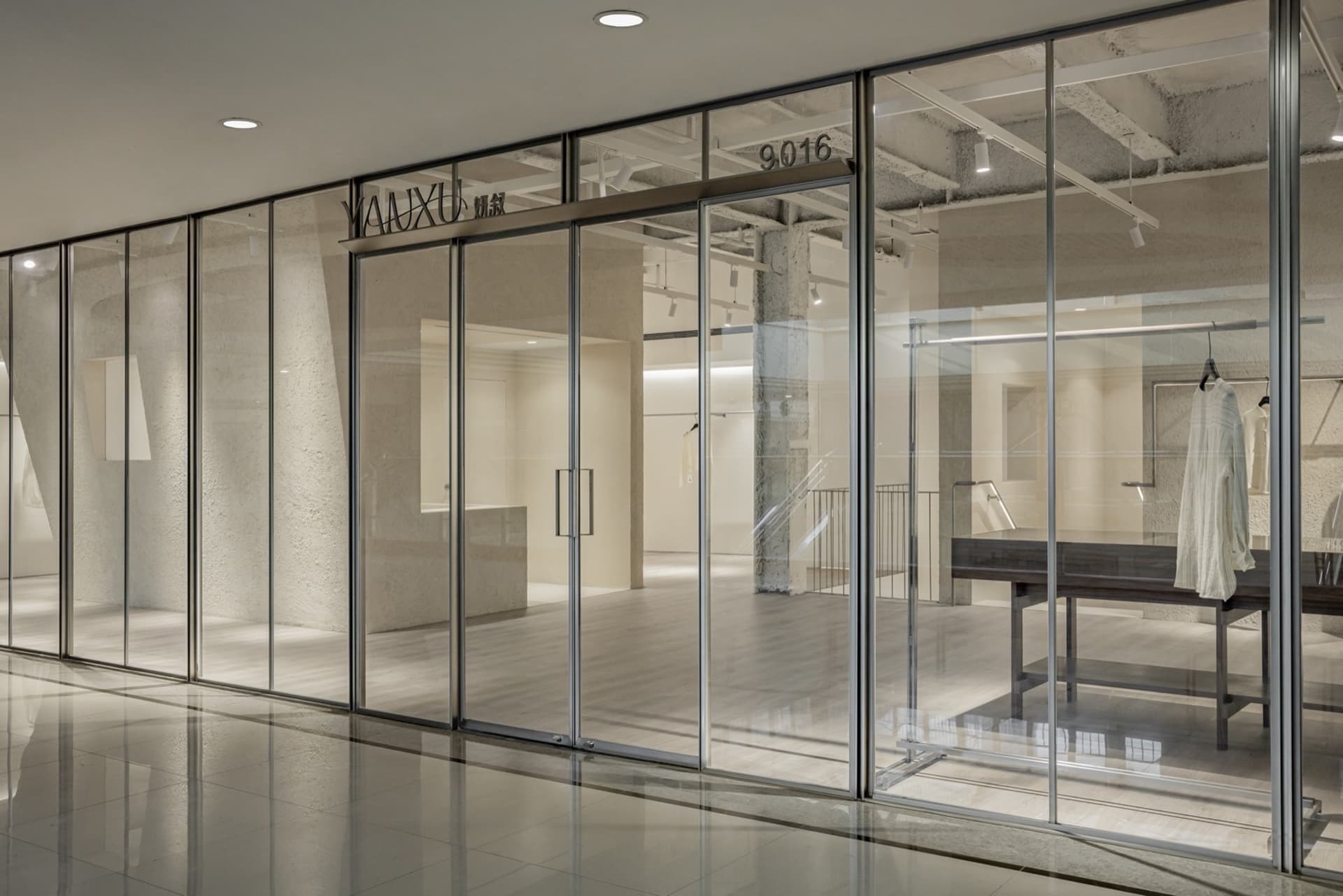 Glass wall of a clothing store displaying garments.