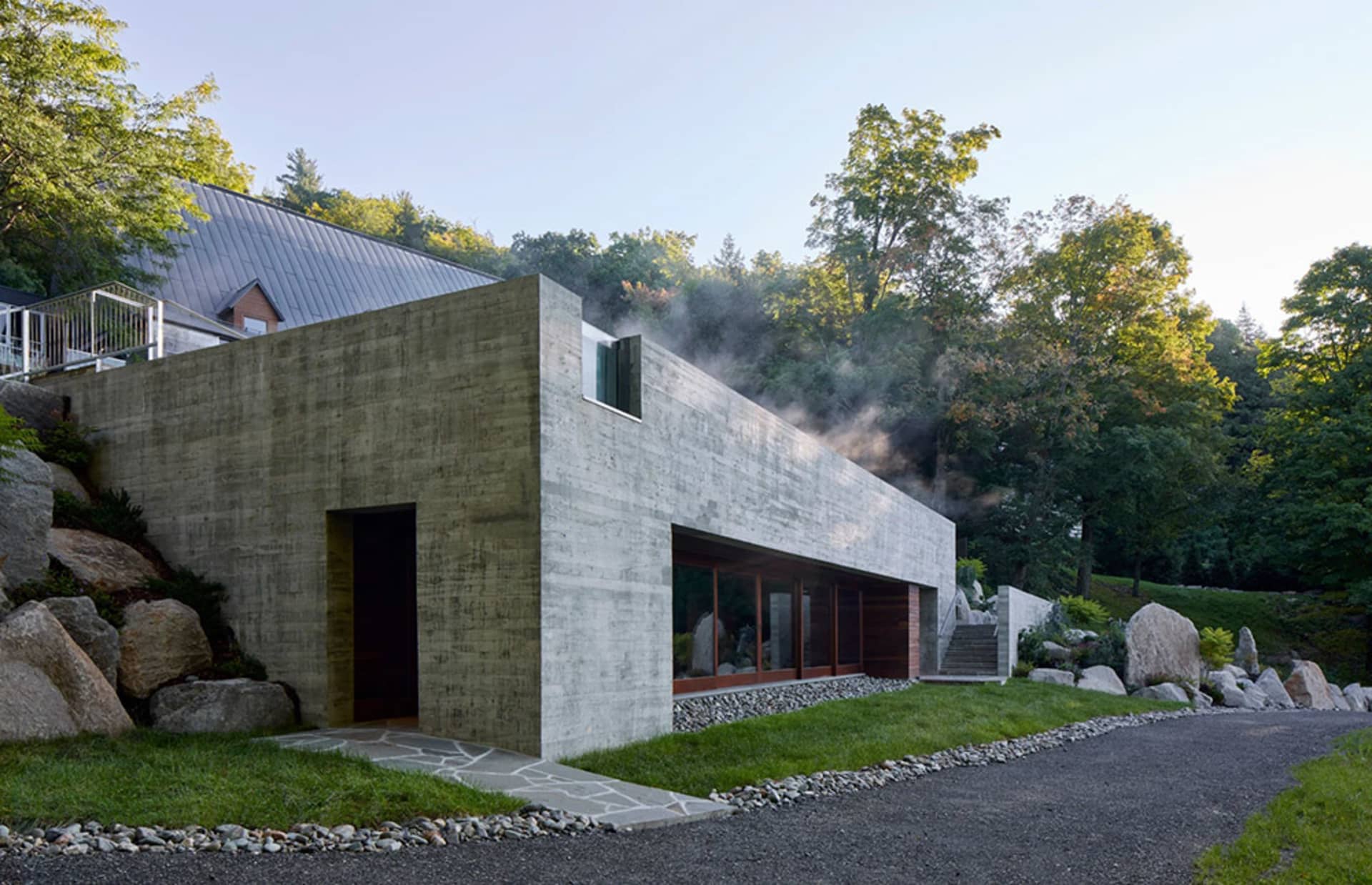 Modern residential home with concrete walls and a glass window on a hillside.