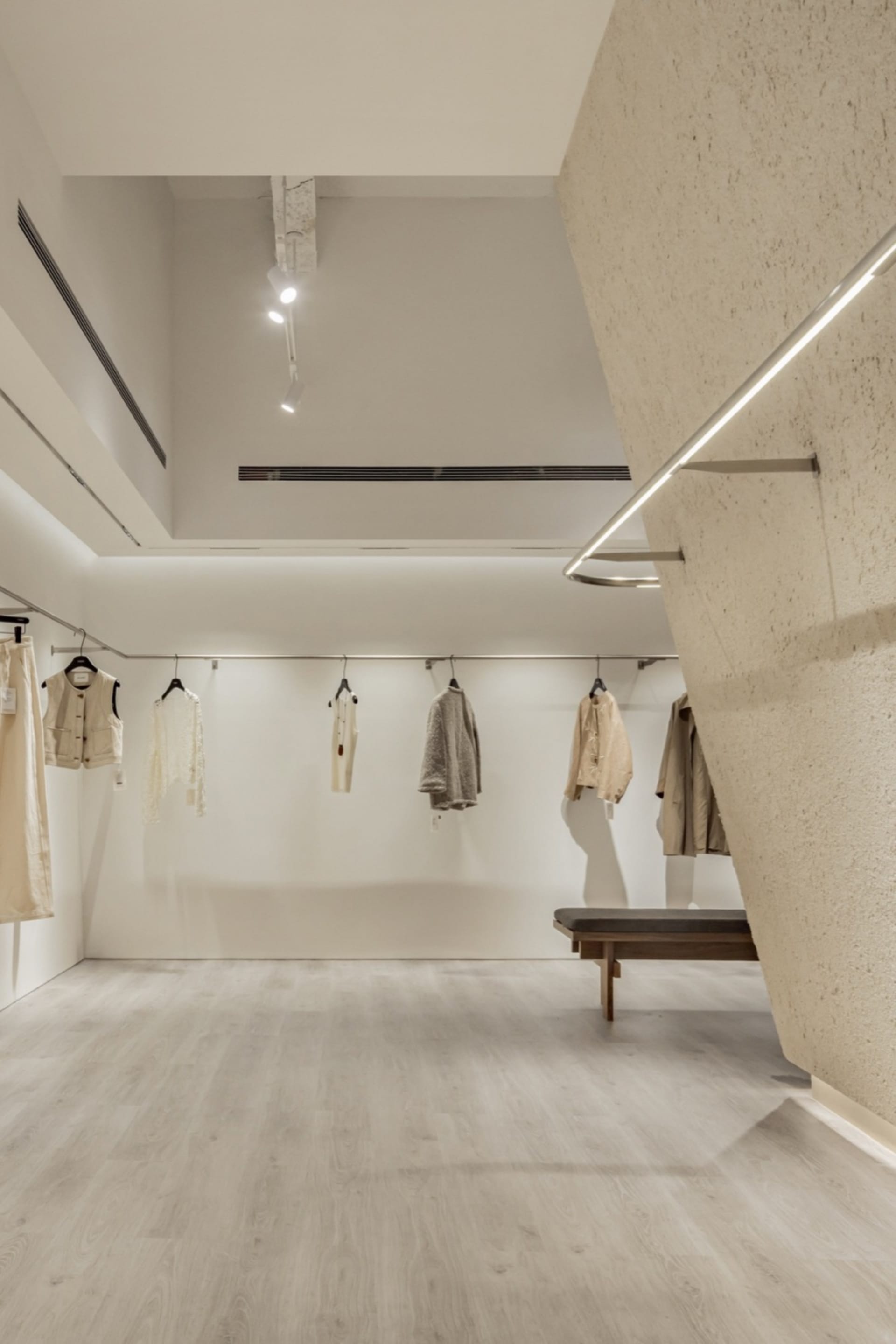 現代零售店室內空間，採用極簡設計、中性色調材料，並陳列服裝。