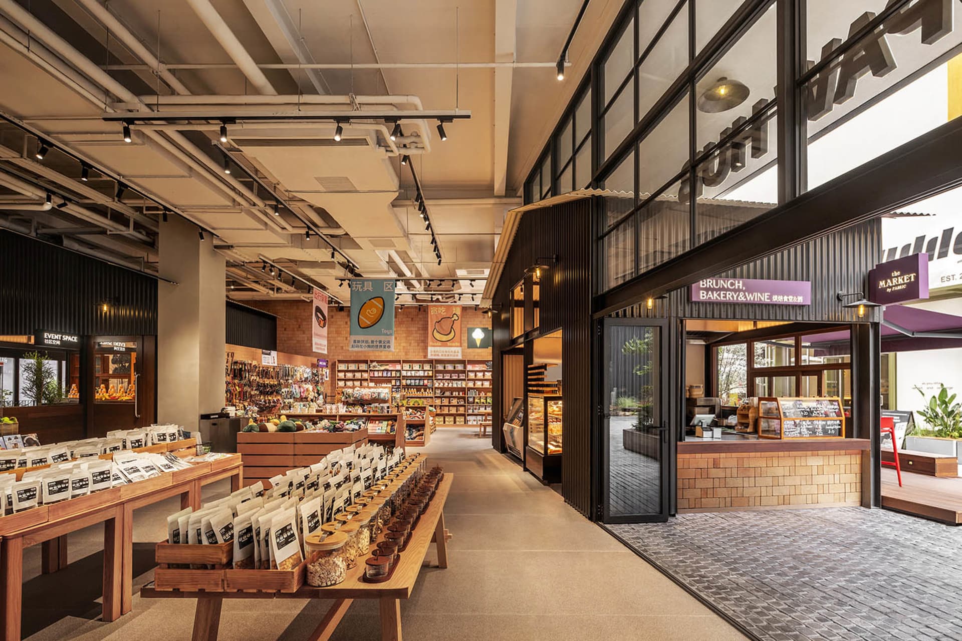 Industrial-style retail space featuring brick walls, wooden tables, metal shelving units, and glass windows.