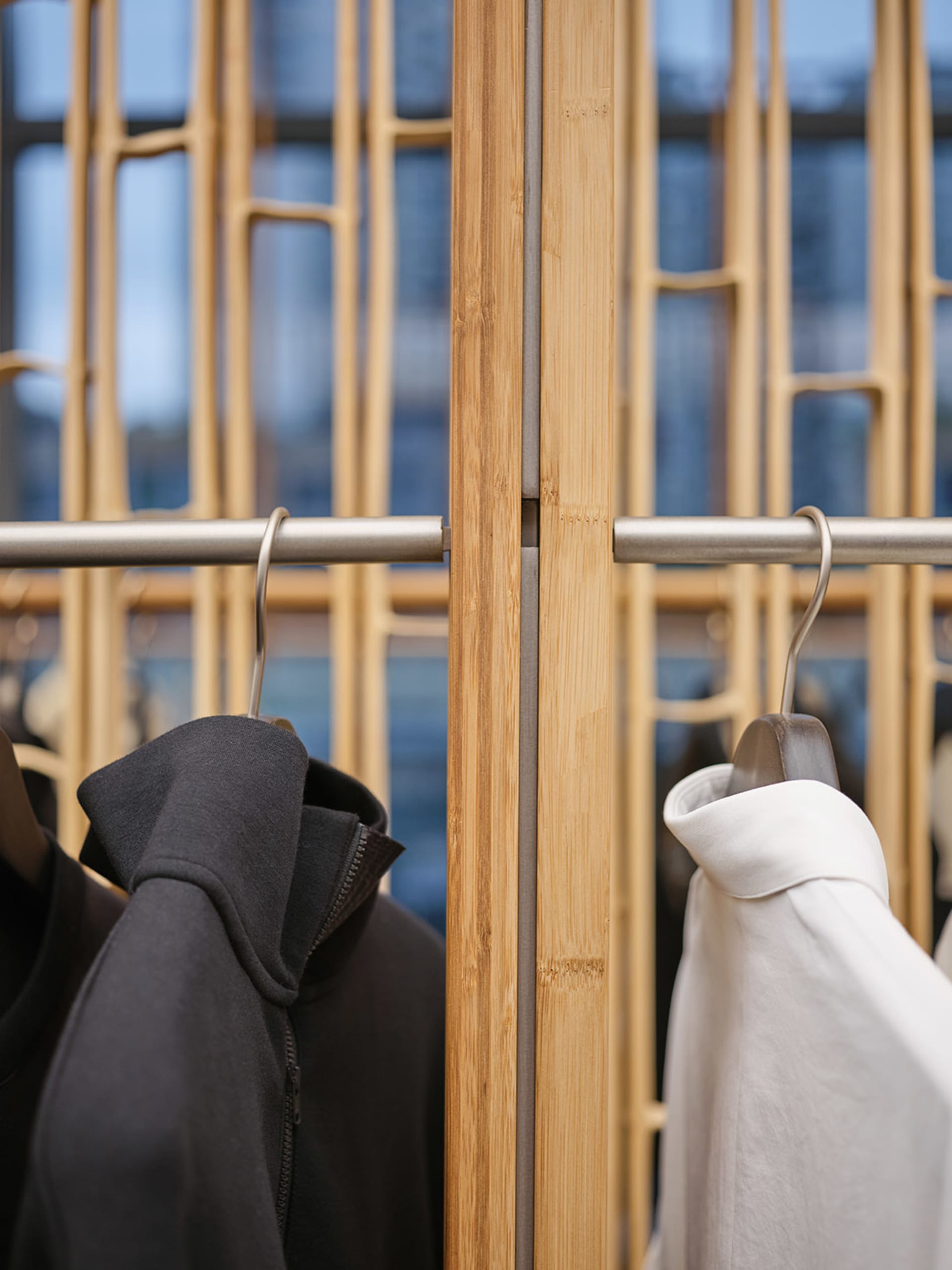 A modern clothing rack made of metal with clothes hanging on it.