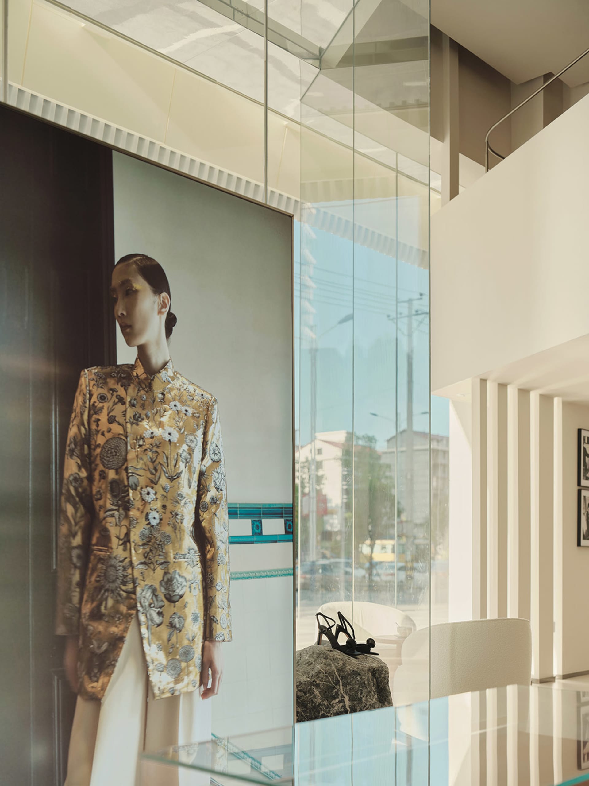 A modern fashion retail interior with a glass window displaying a high-end outfit.
