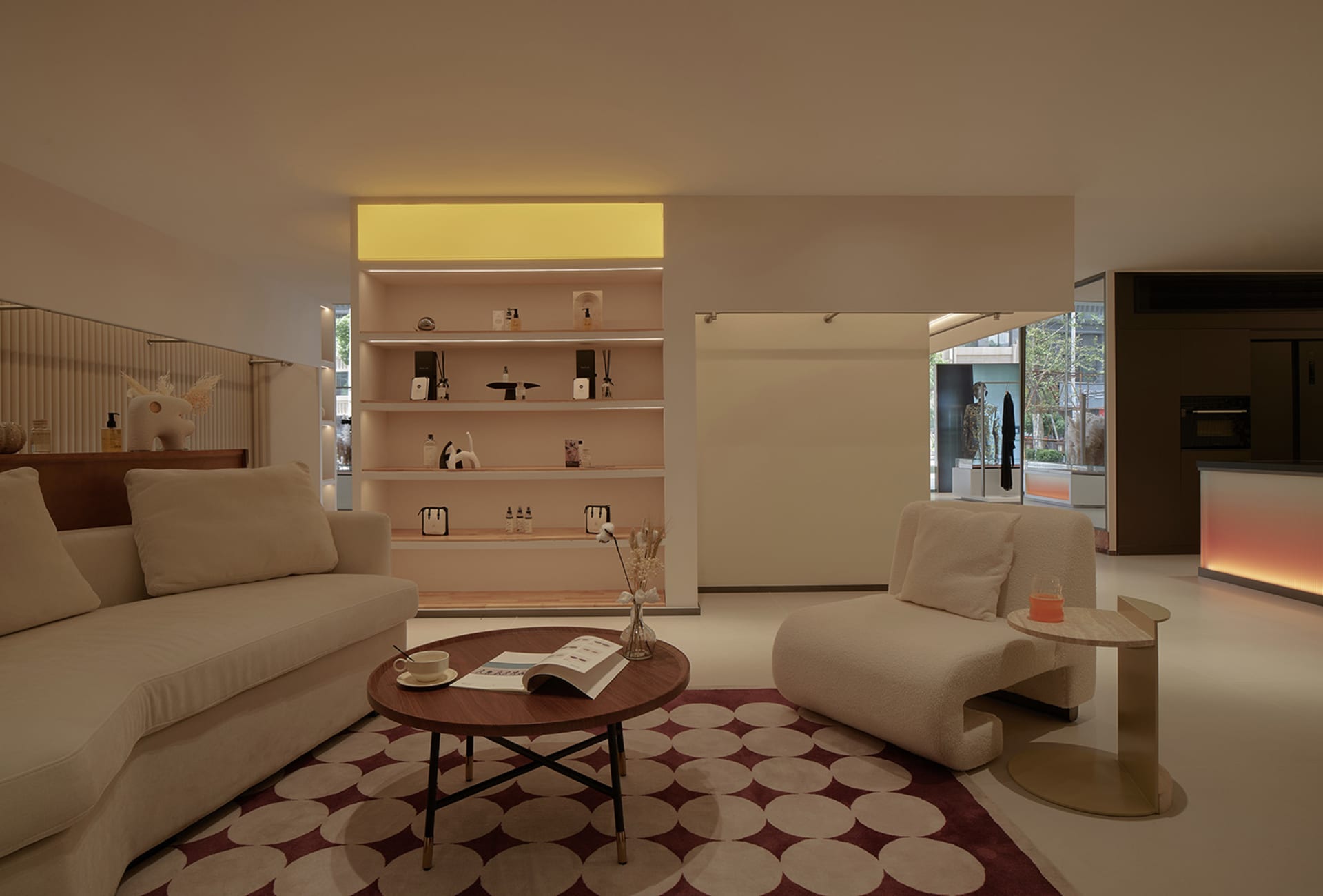A modern living room with a neutral color palette, featuring a round wooden coffee table, white sofas, and a patterned and co