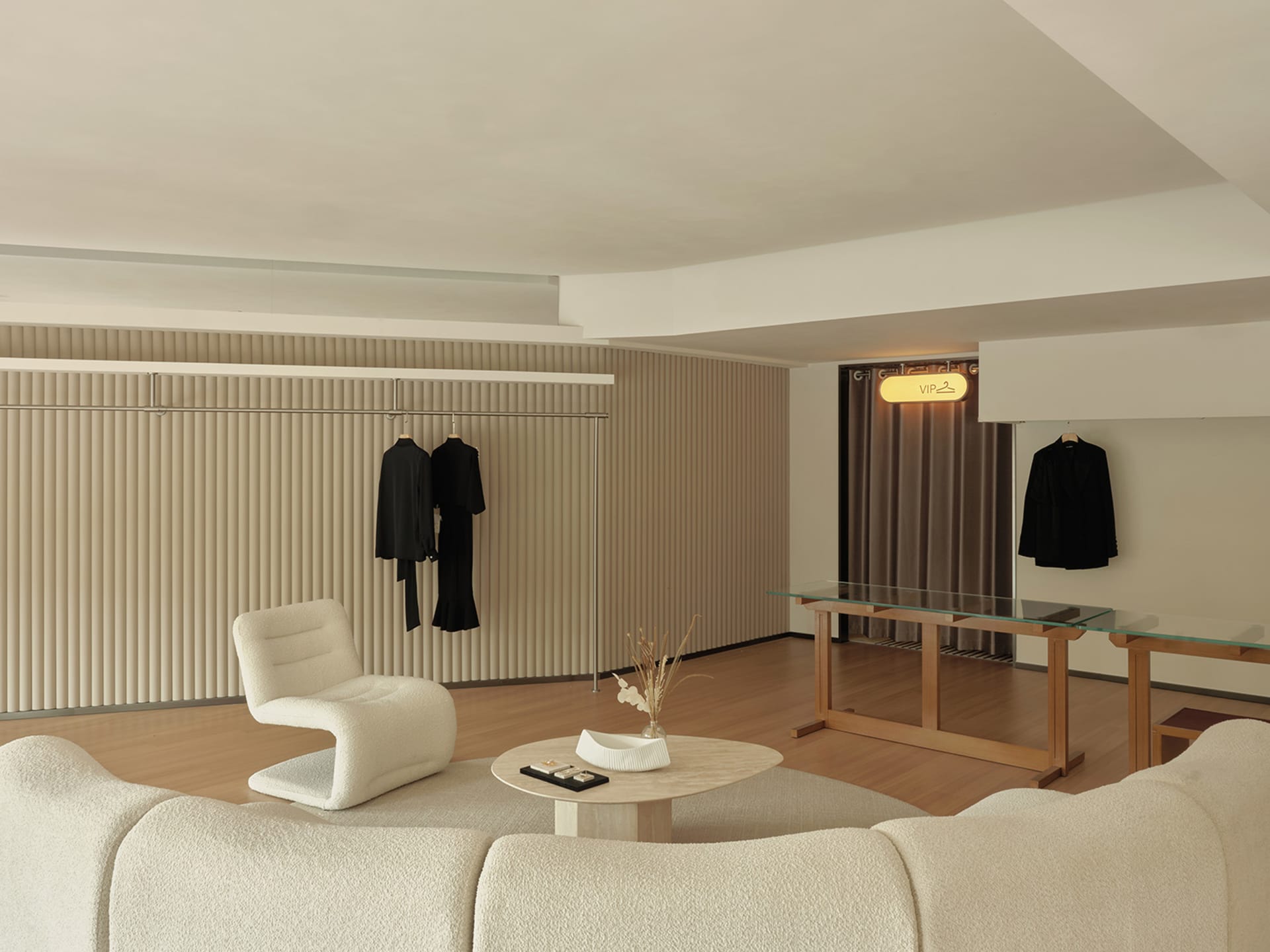 Modern retail store interior featuring wooden flooring, glass display cases, and fabric seating.
