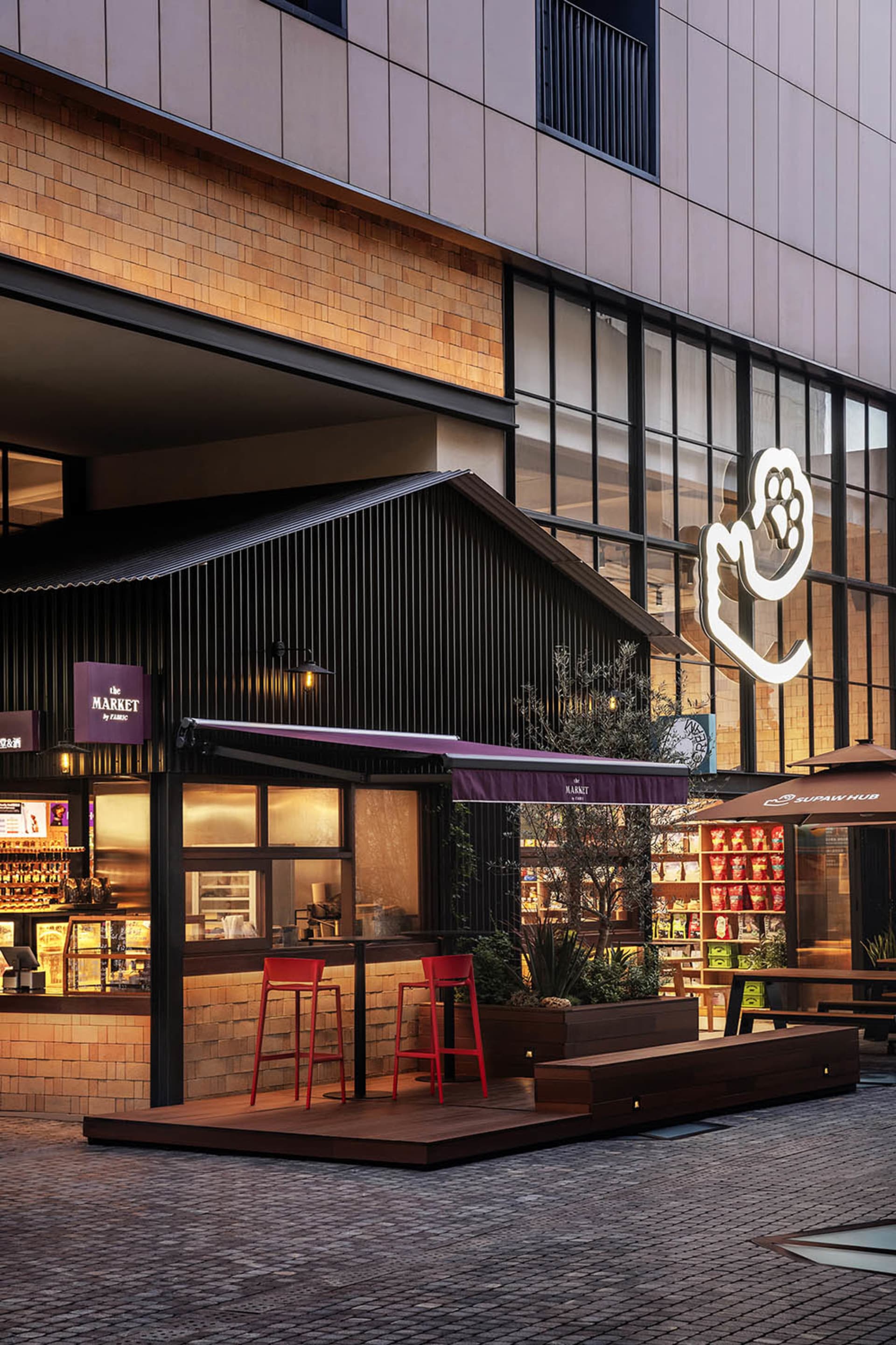 戶外座位區搭配紅色圓凳、磚牆店面以及大型玻璃窗。