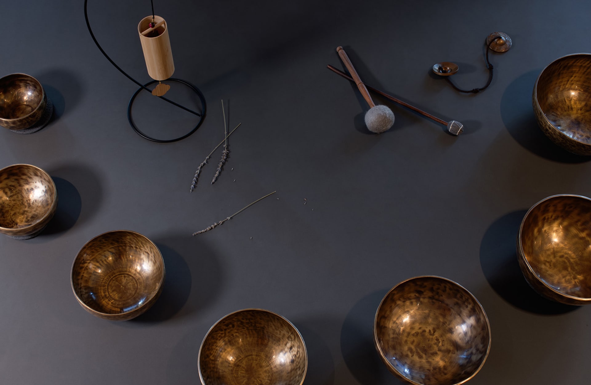 A display of metal bowls arranged on a dark surface with additional decorative objects and tools.