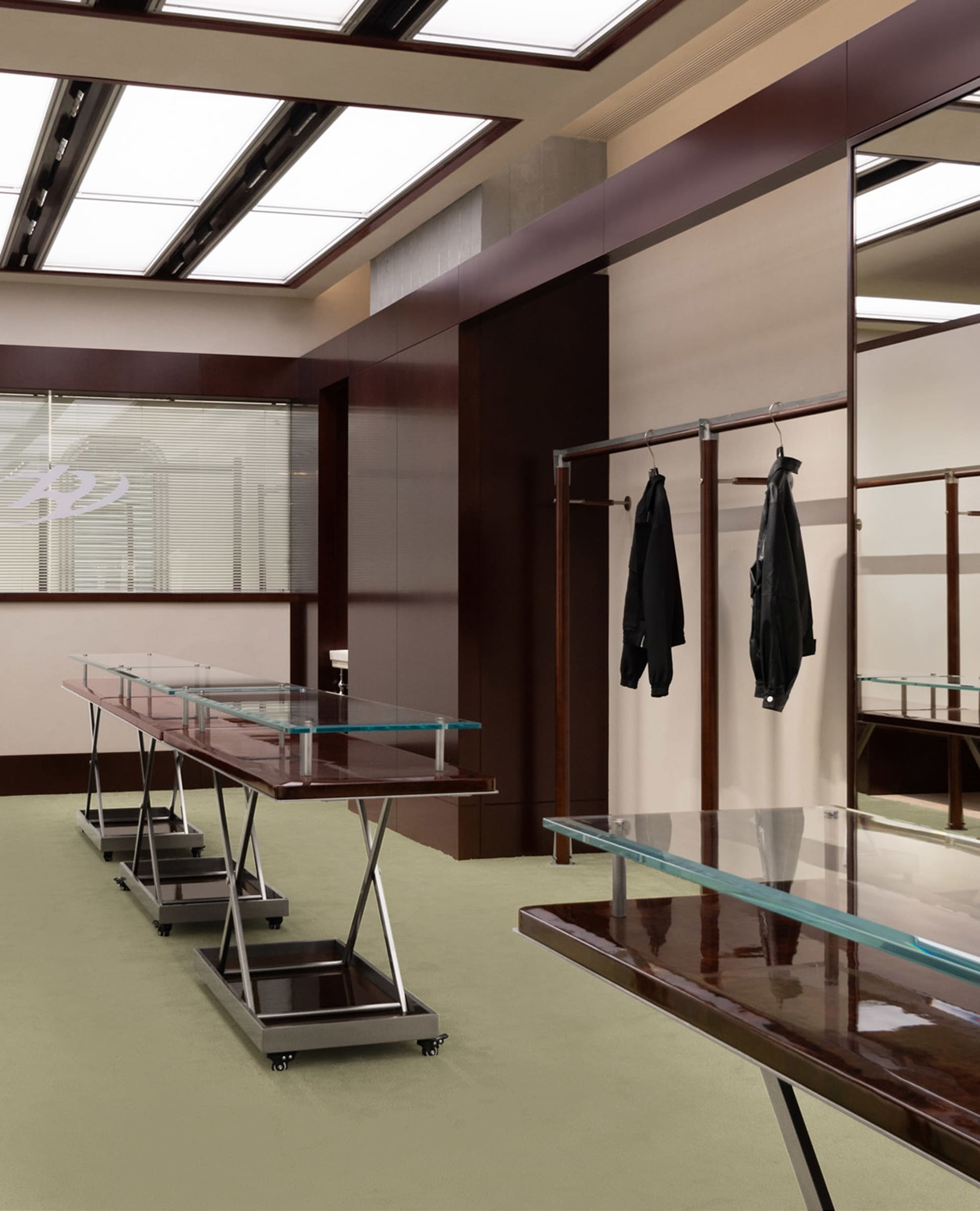 Modern clothing shop with glass tables and metal railings.
