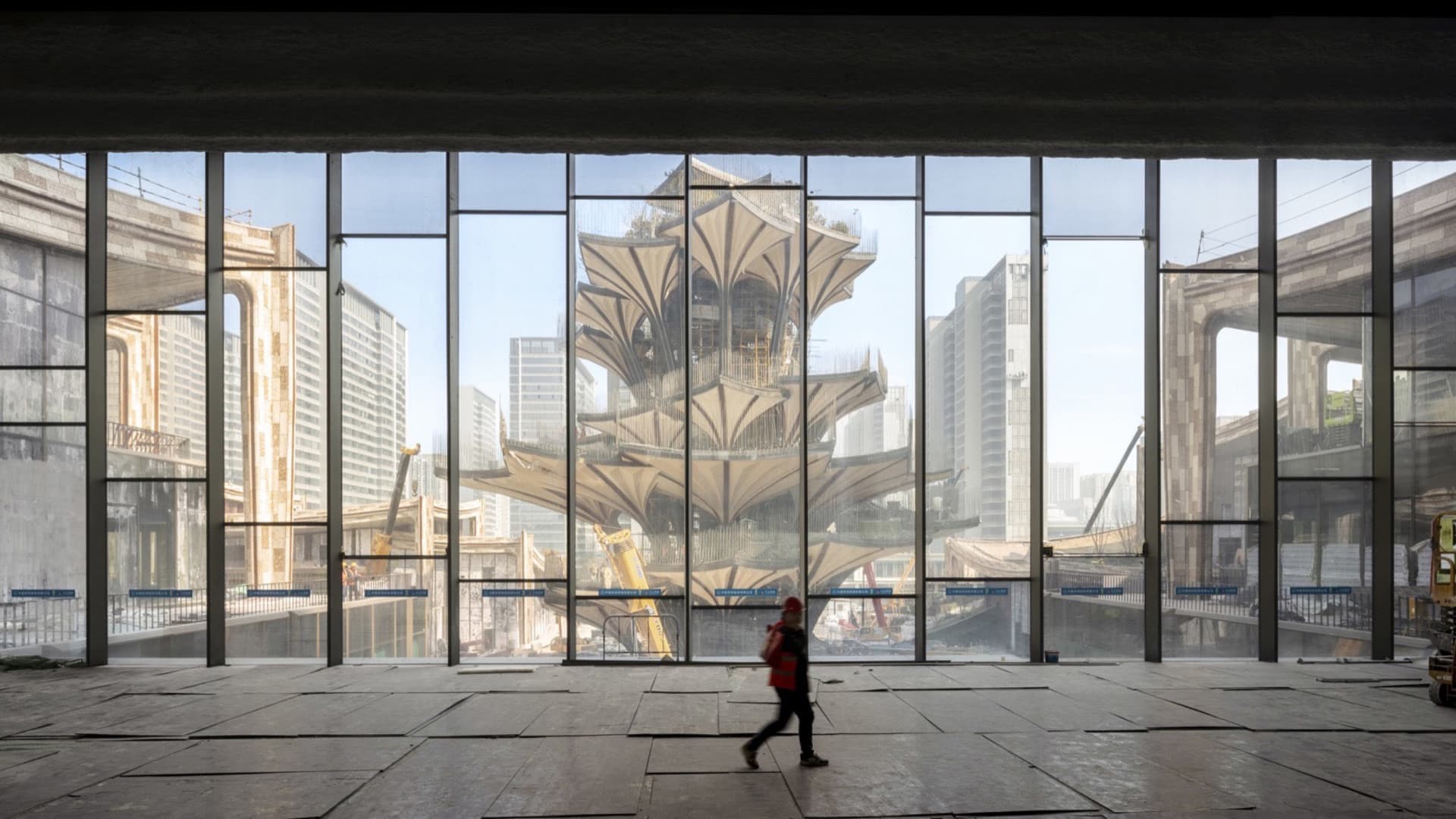 一張照片顯示工地內的大型玻璃窗,反射出周圍的城市景觀,包括一座模