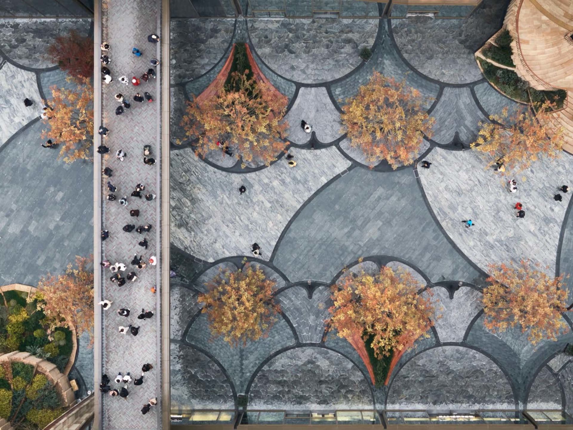 Overhead view of a modern public space featuring decorative tiles, concrete walkways, and wooden structures.