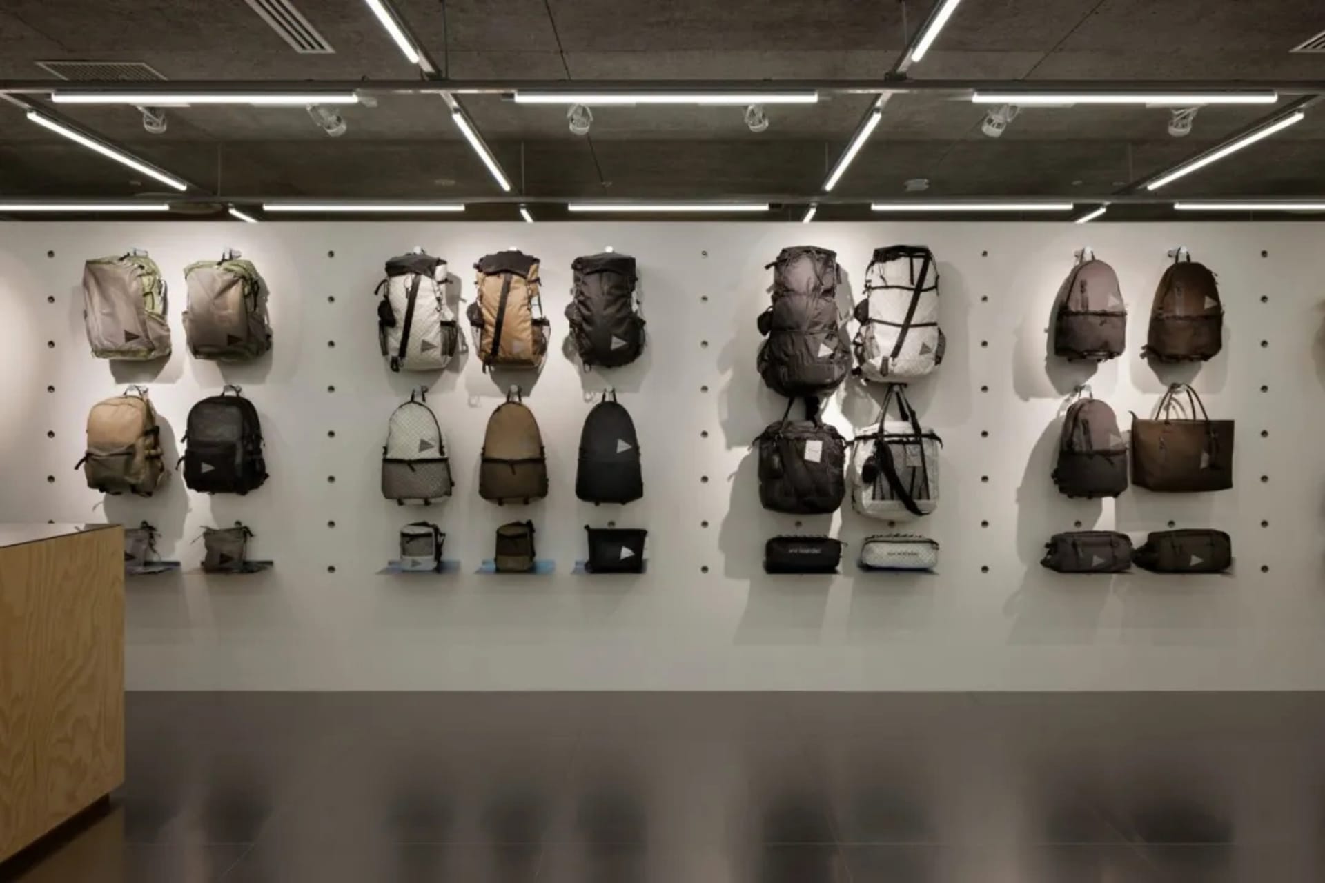 A row of backpacks and bags hanging on a pegboard in a retail storefront.