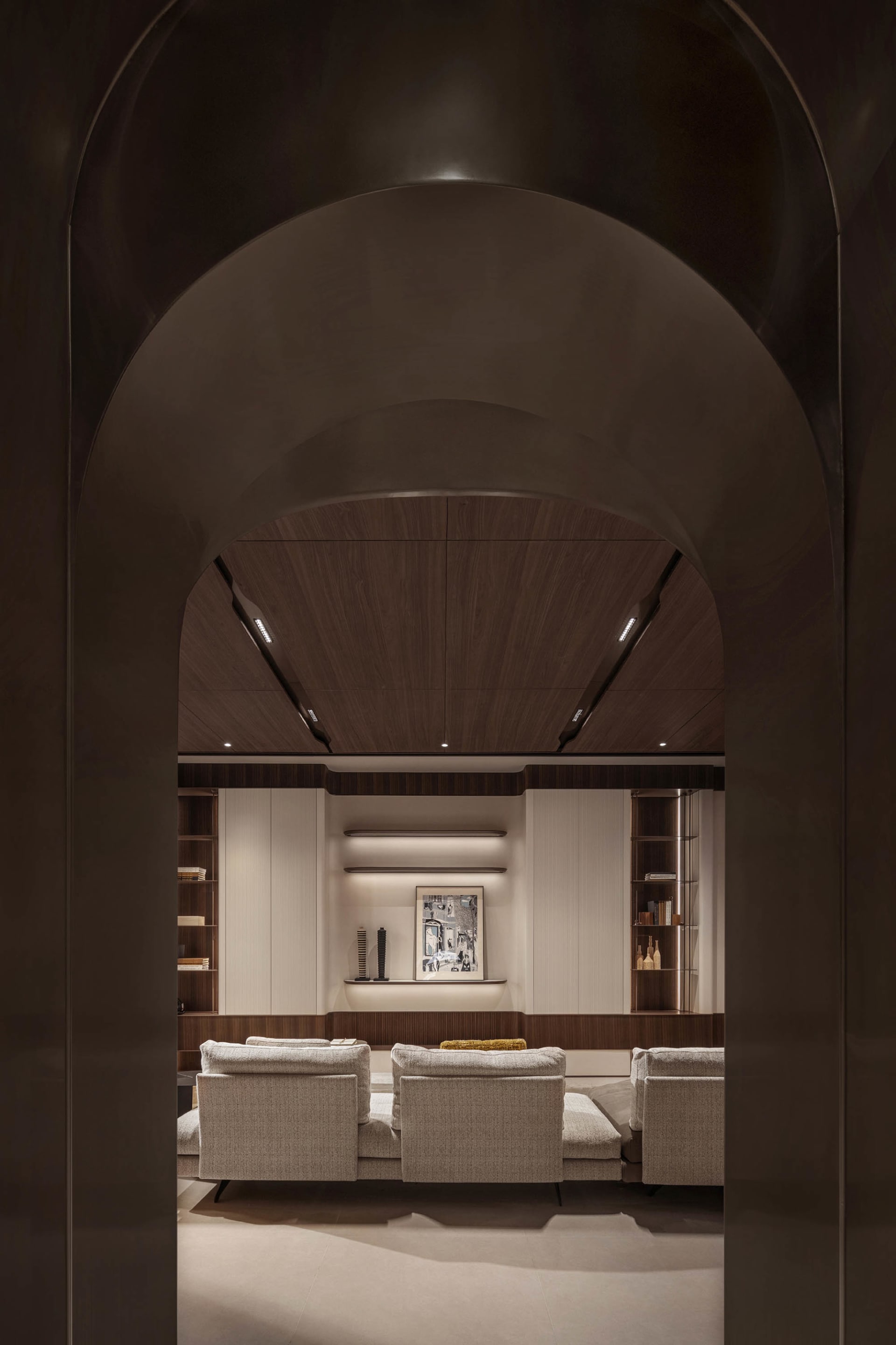 A modern living room featuring wood-paneled walls, upholstered furniture, and minimalist decor.