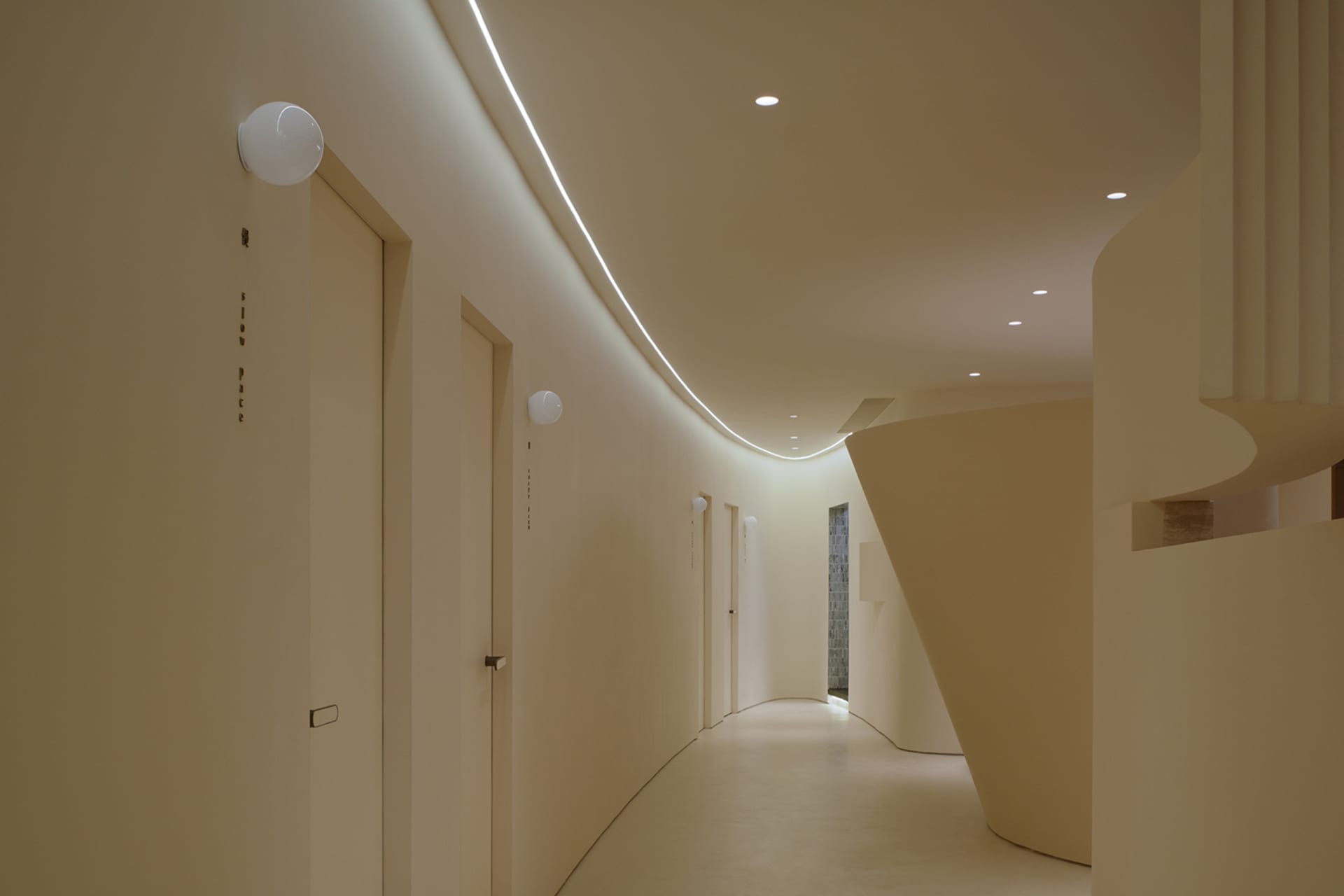 A modern hospital hallway with neutral-colored walls, a smooth floor, and curved architectural elements.