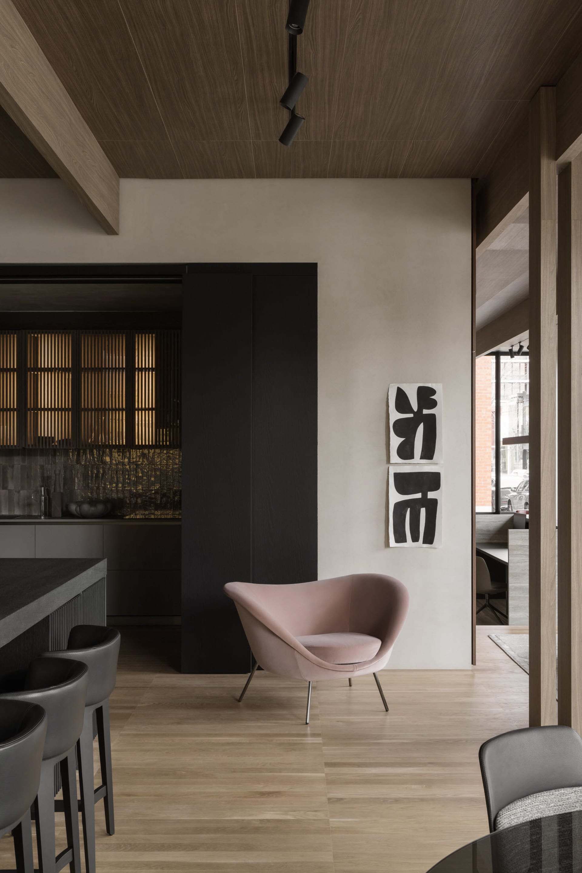 Modern living room featuring minimalist decor with wooden furniture and a pink armchair.