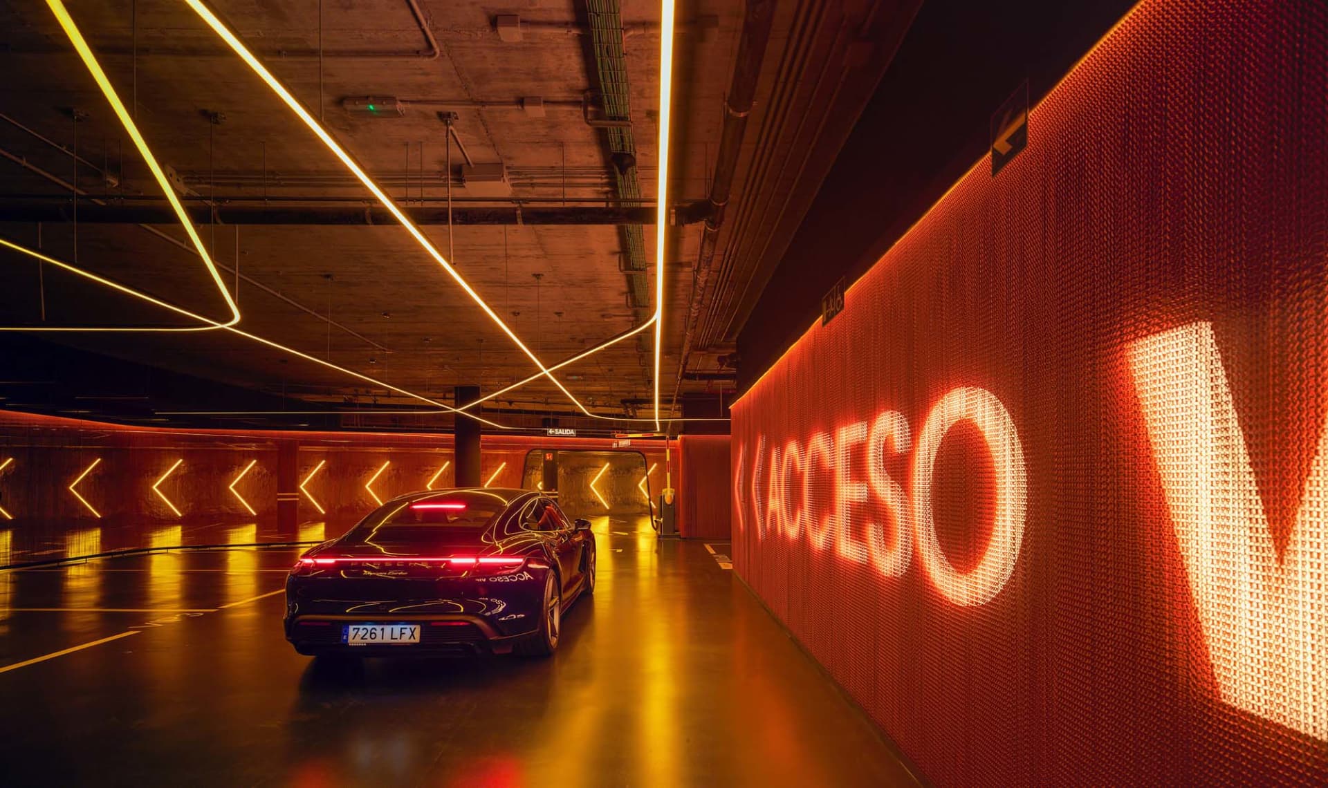 A modern parking garage interior with metallic finishes and neon lighting.