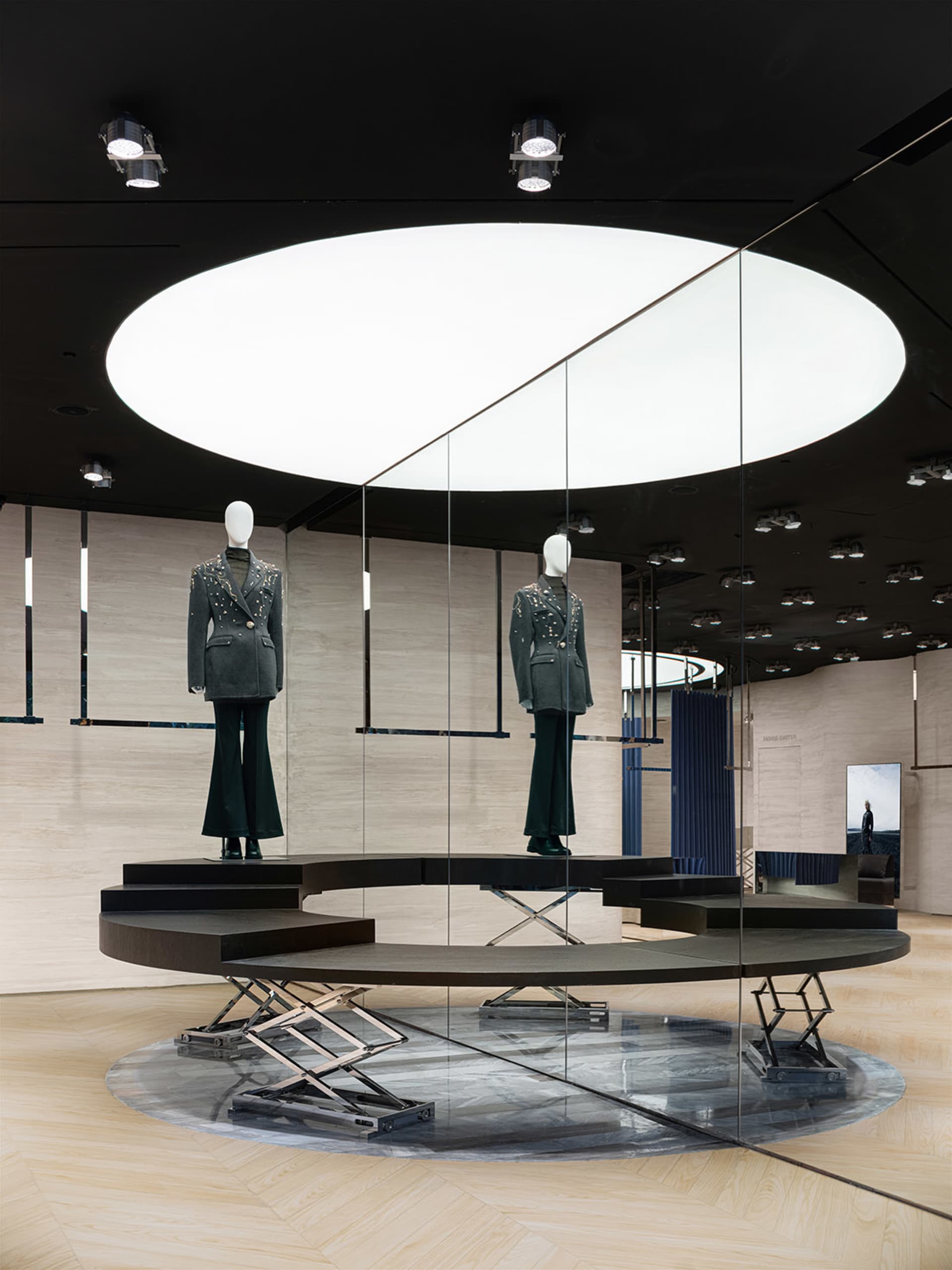 現代時尚展示，兩具穿著設計師服裝的人體模型，以及黑色天花板上的圓形燈具