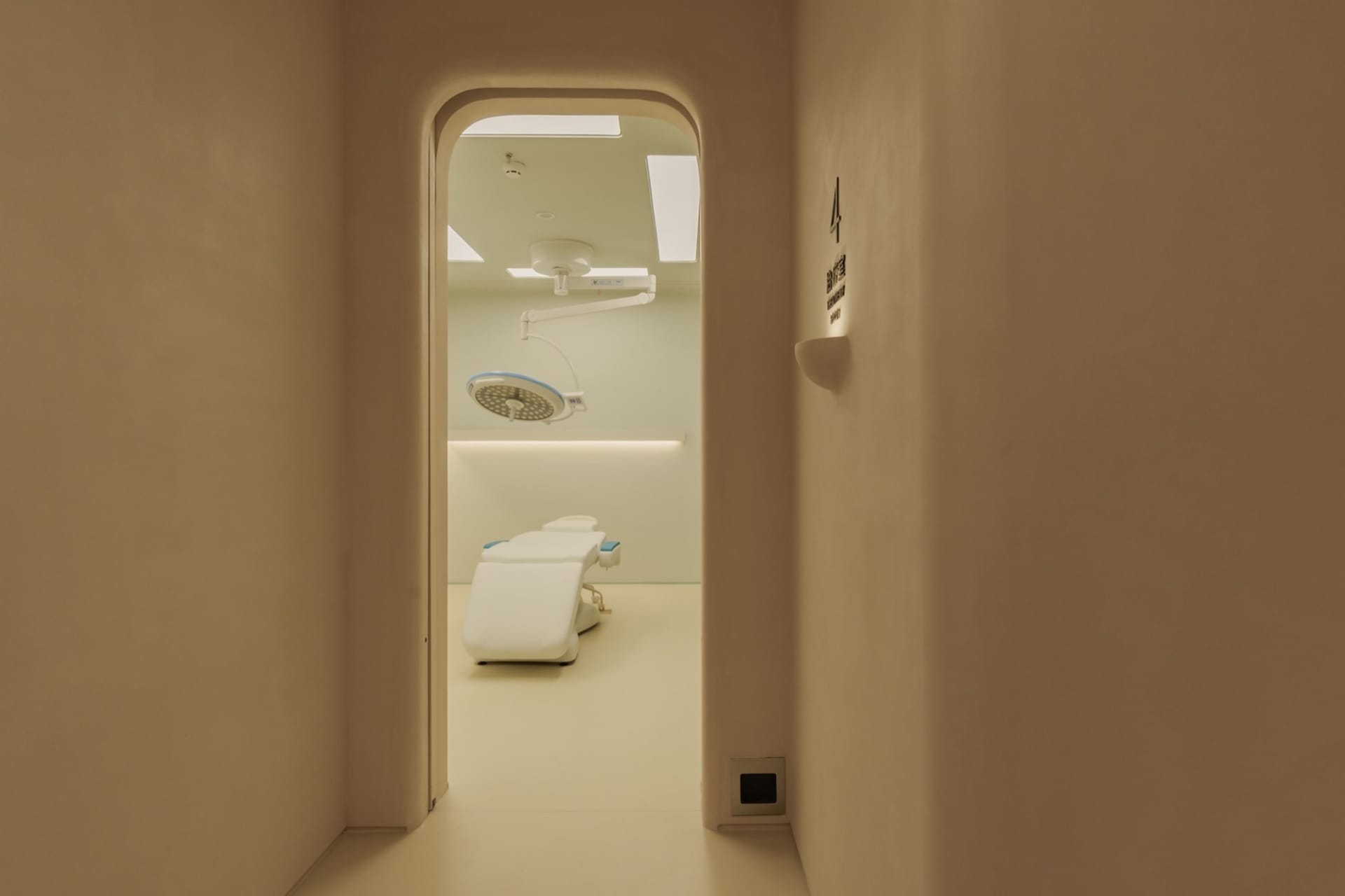 A minimalist hospital room with white furniture and a white ceiling.
