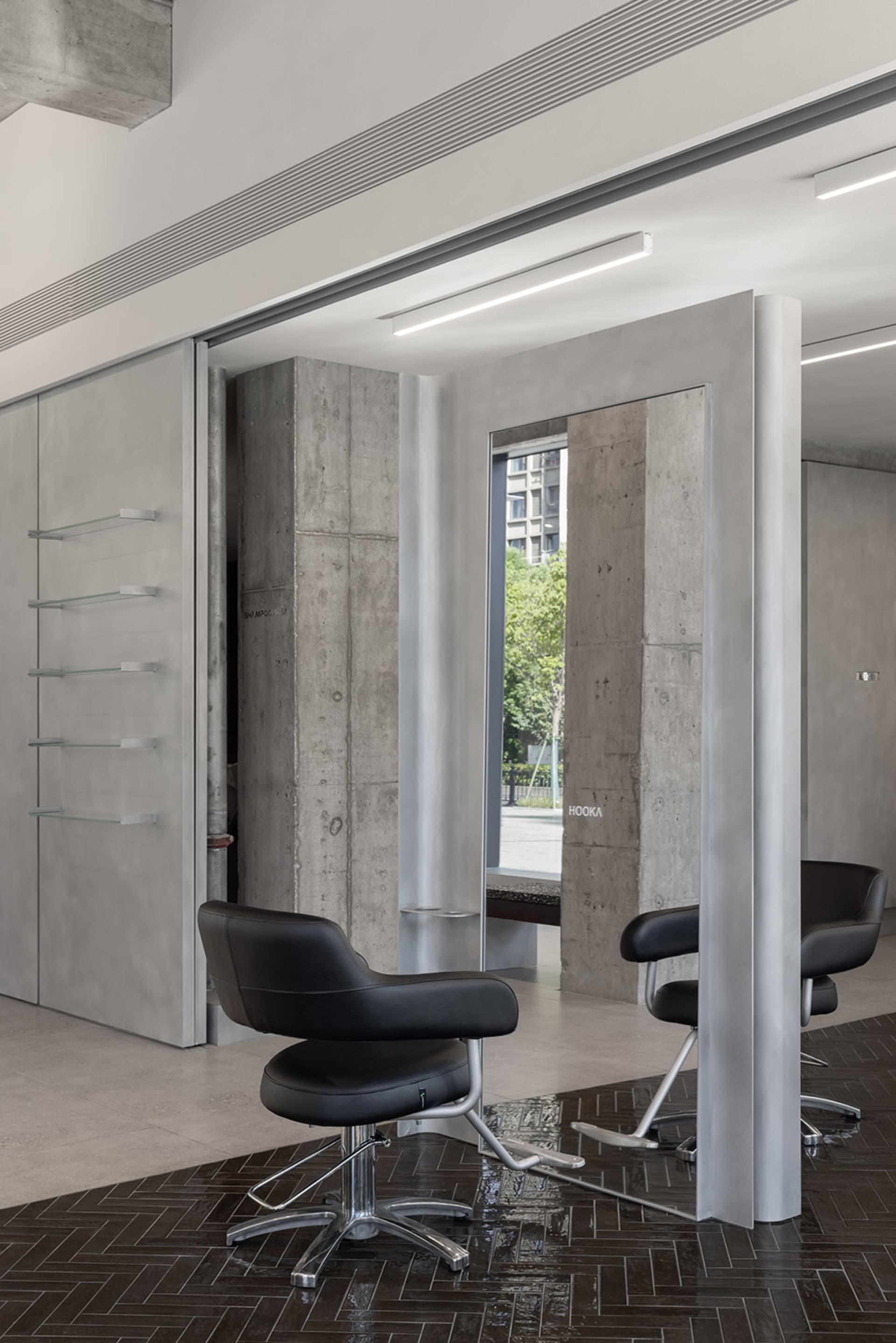 An industrial-style salon interior featuring concrete walls, black furniture, and a modern design aesthetic.