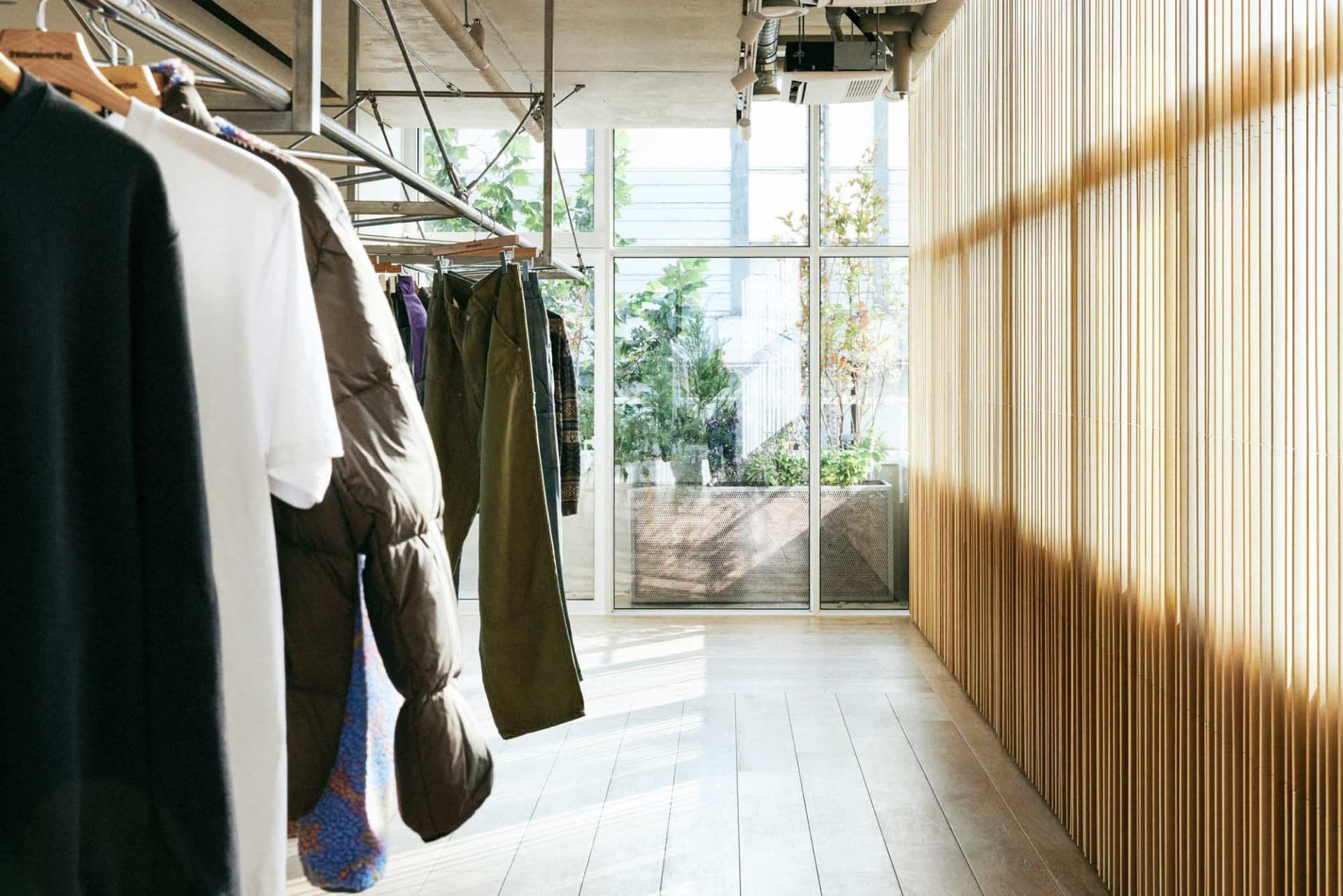 現代服飾店室內空間，木質牆面搭配服裝展示架。