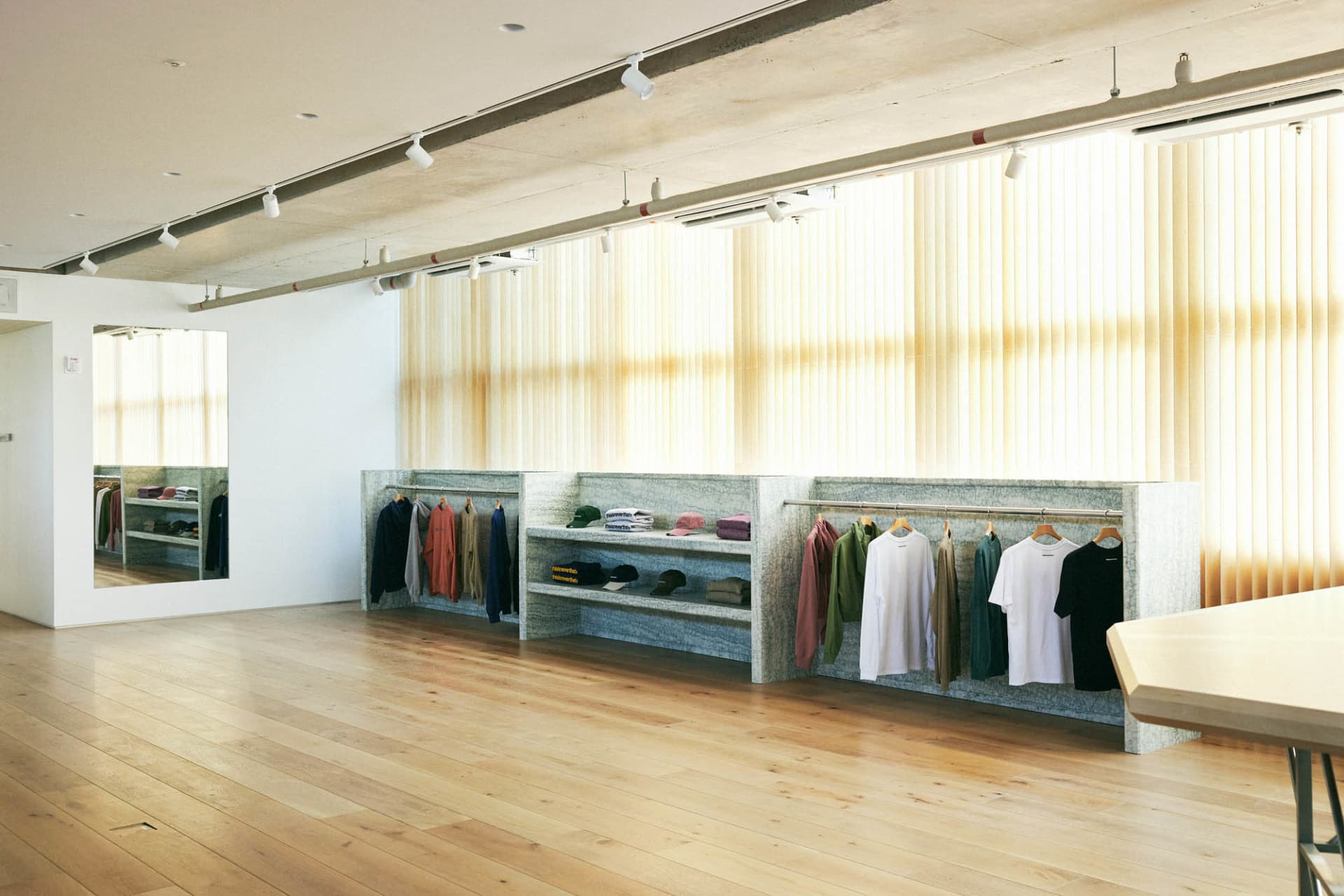 A modern retail space featuring a concrete shelf with various clothing items hanging on it.