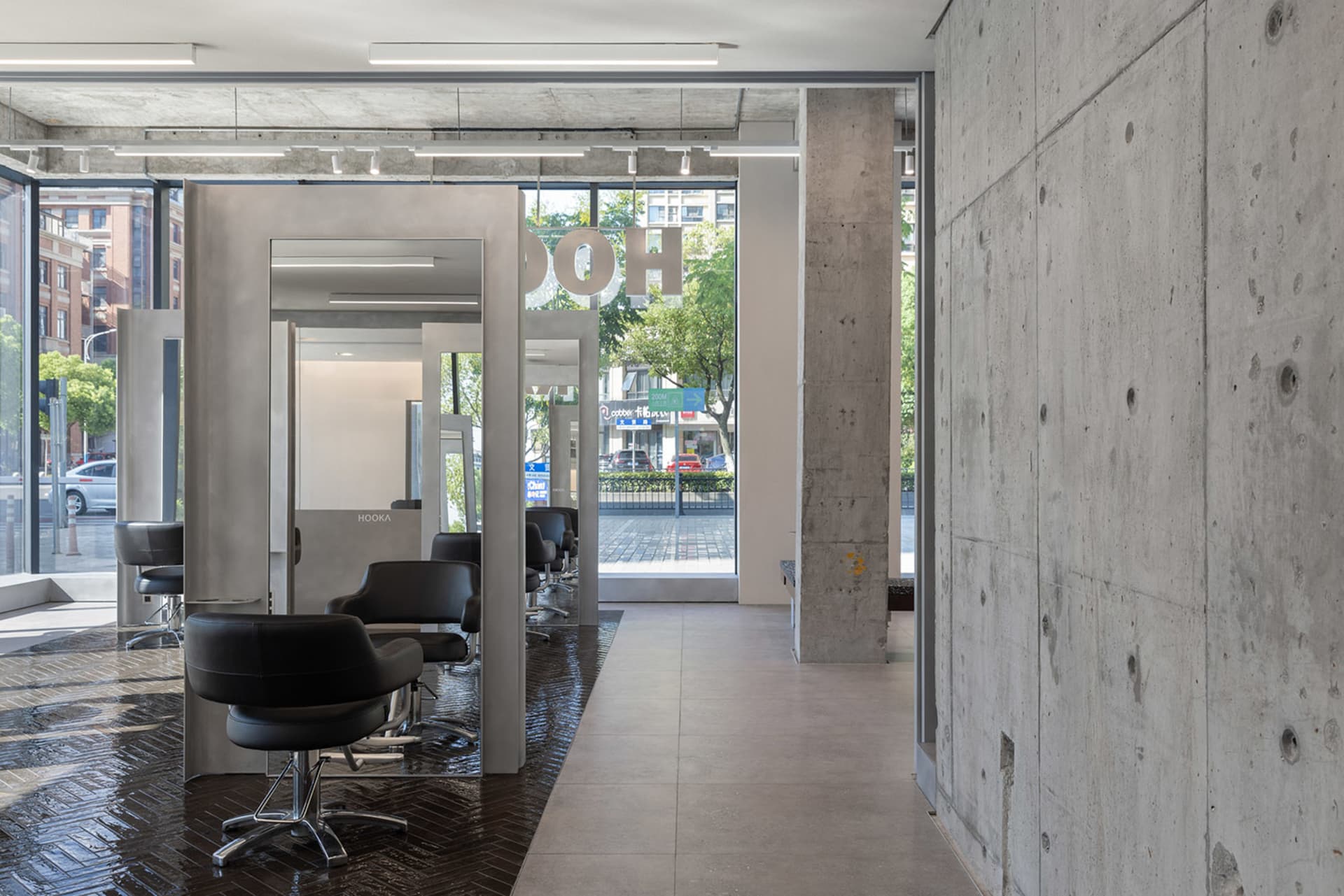 Modern salon interior with black chairs, concrete walls, and glass elements.
