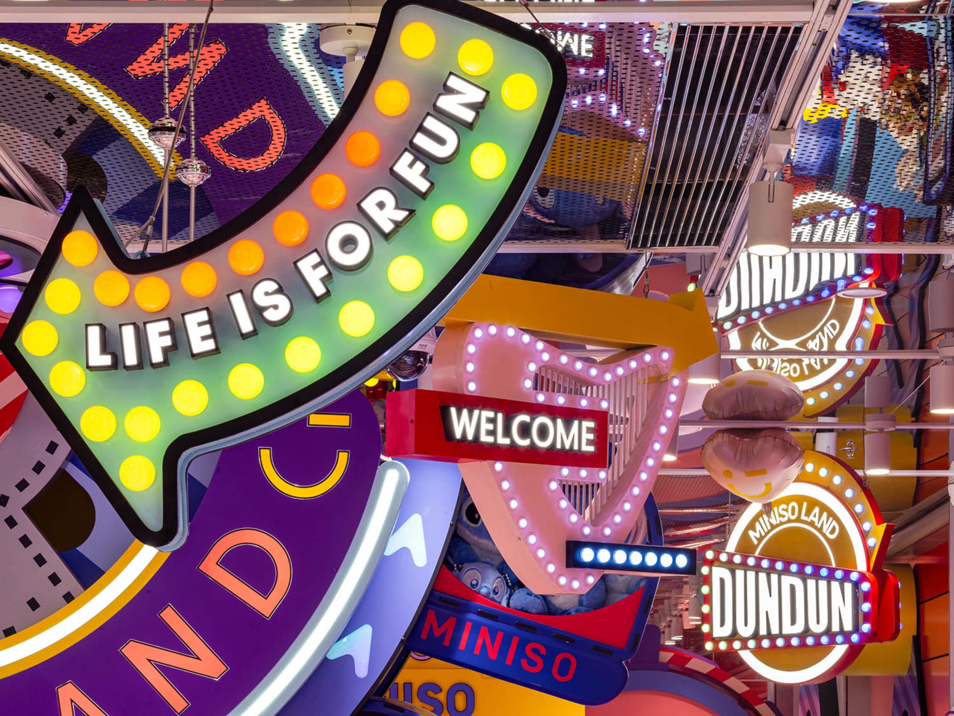 An array of colorful, illuminated retail signage in a vibrant interior setting.
