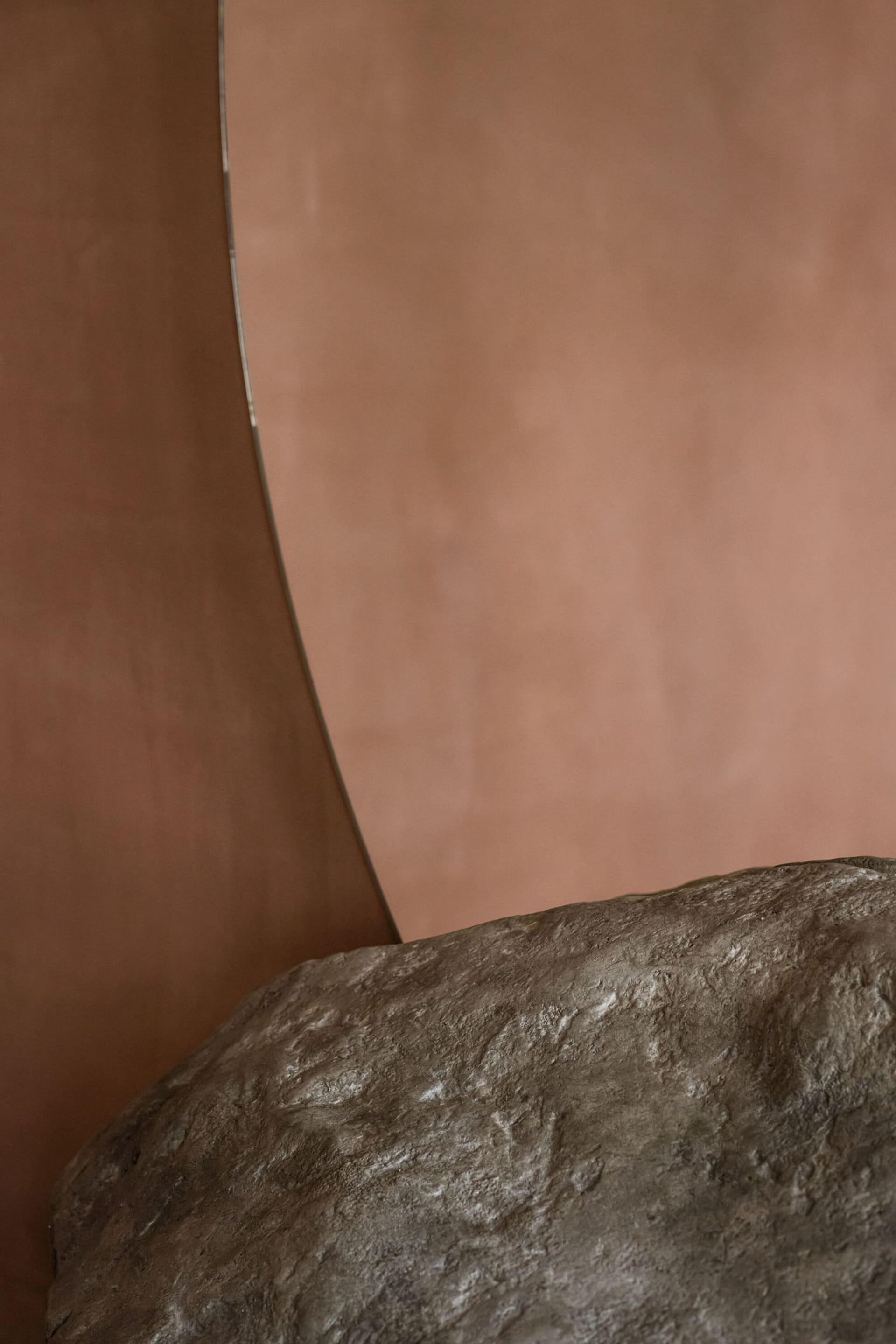 Minimalist bedroom with stone furniture against a rose-colored wall.