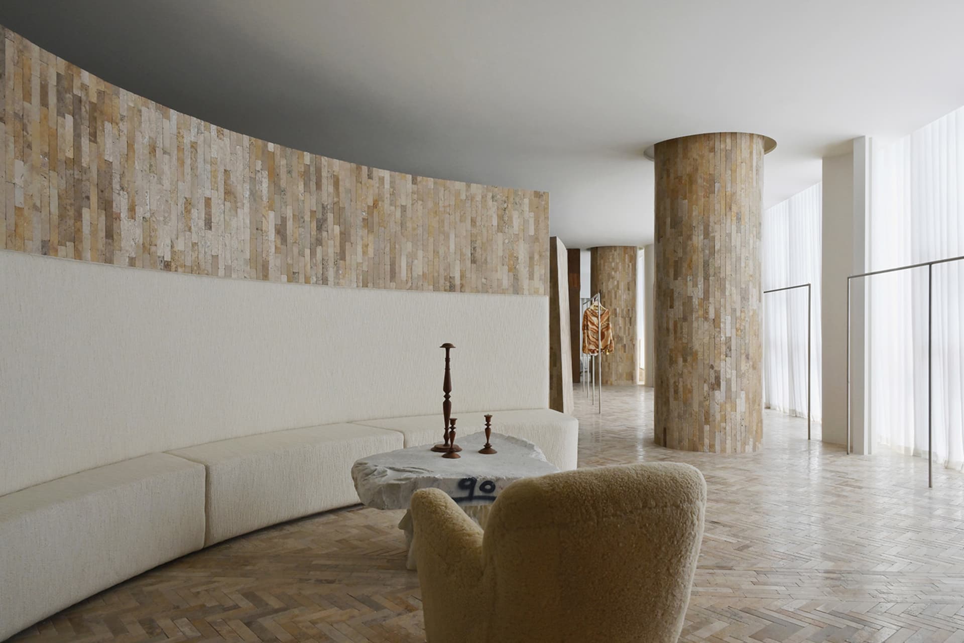 A modern storefront designed with concrete elements, featuring a curved wall and a circular wooden pillar.
