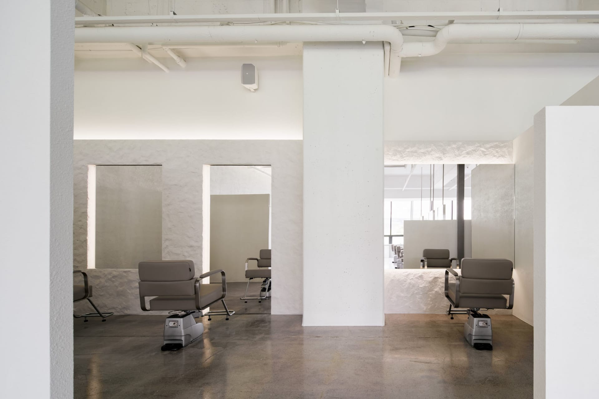 Industrial-styled salon interior with concrete walls and minimalist design.