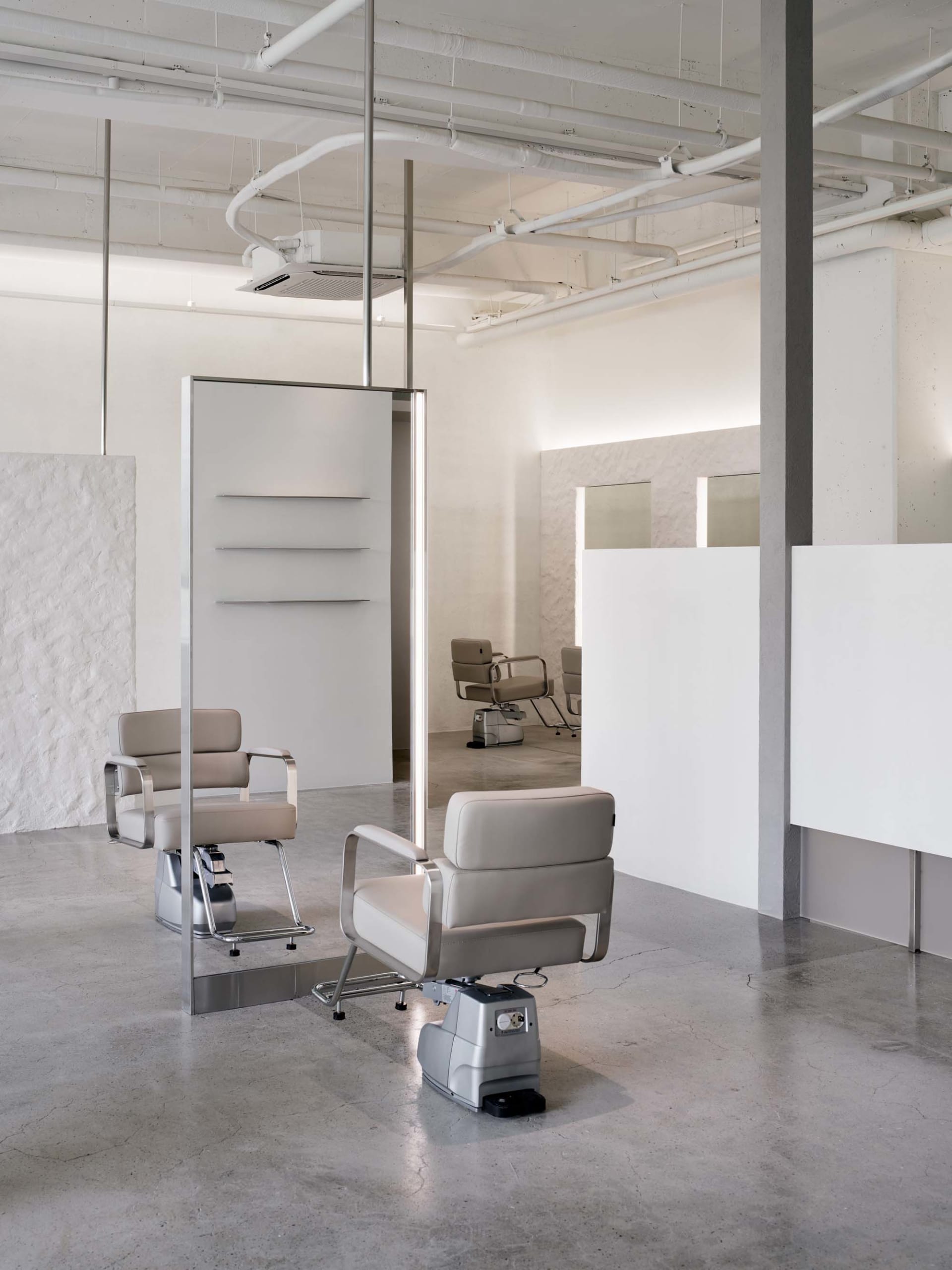 A modern industrial hair salon interior with concrete walls and minimalist design.