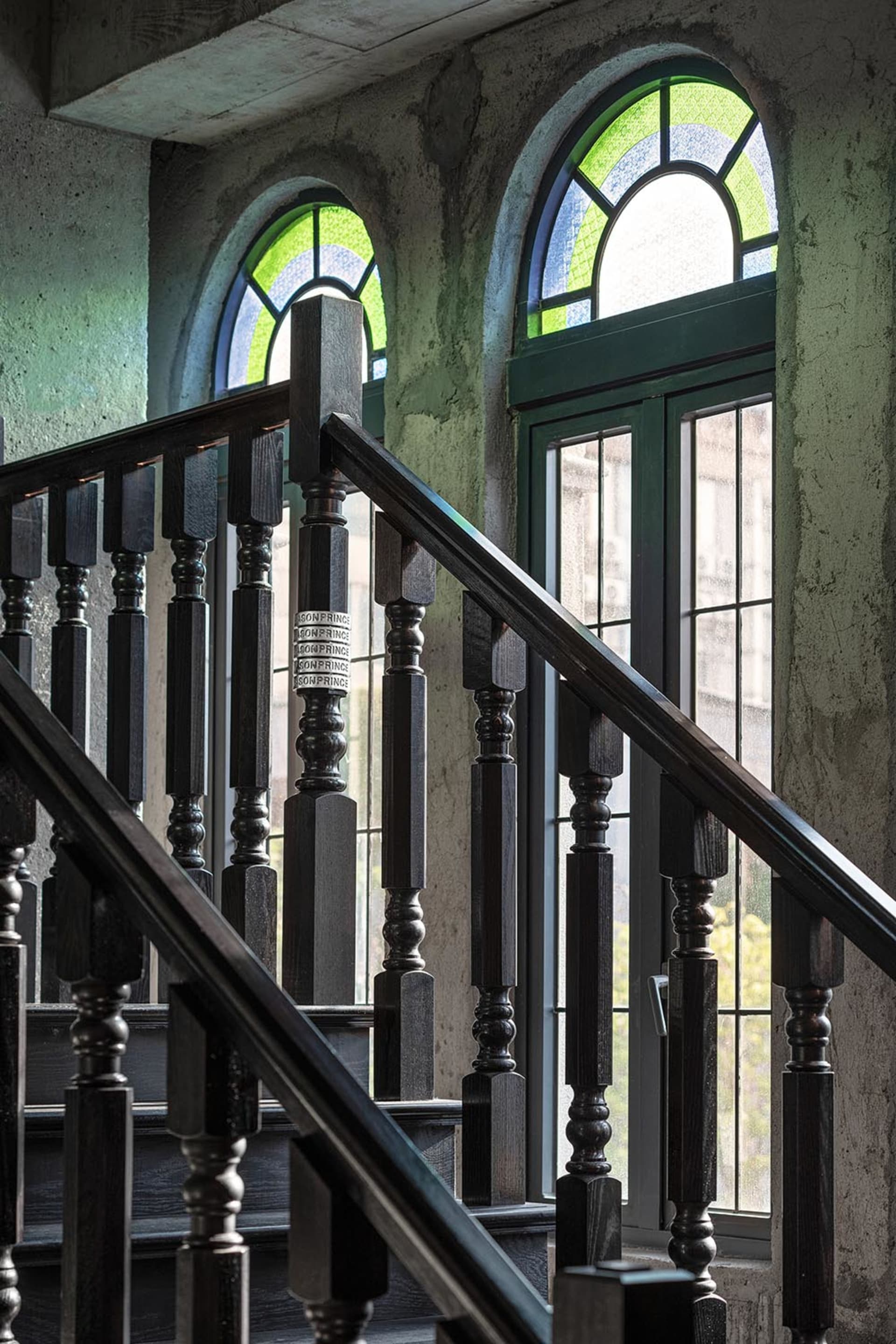 Industrial-style staircase with wooden balusters and glass-paneled windows.