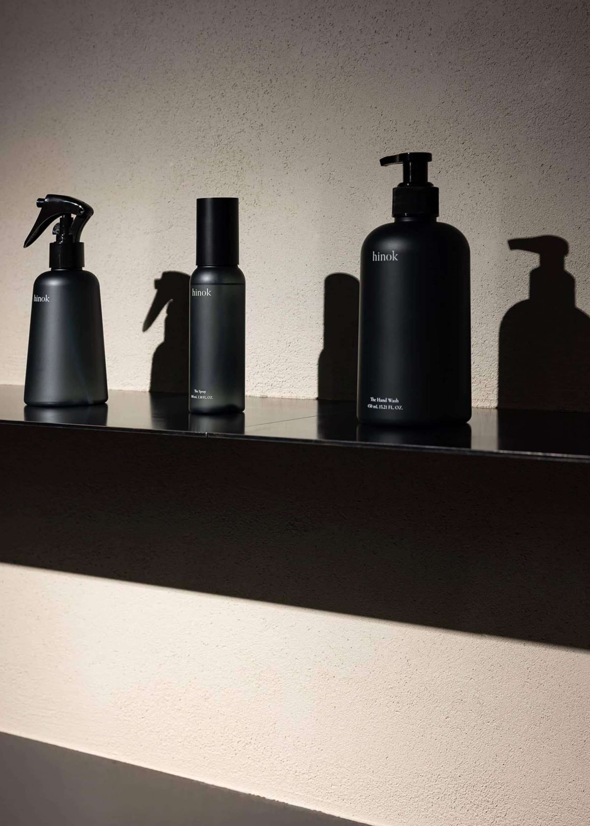 Modern black bathroom accessories with glass material on a sleek black shelf.